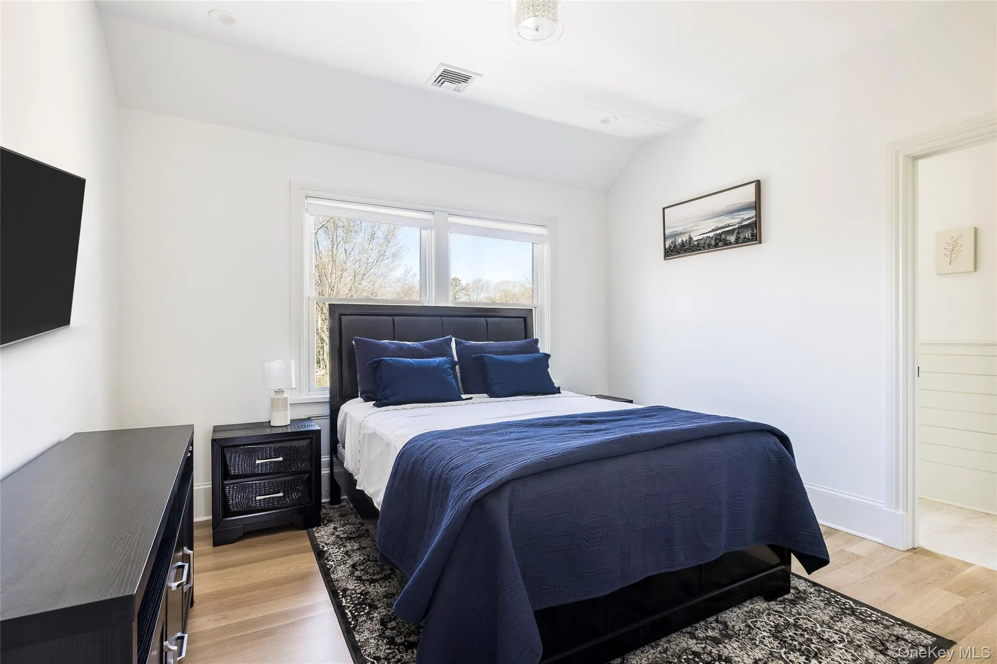 Bedroom featuring lofted ceiling, light wood finished floors, and visible vents Bedroom featuring lofted ceiling, light wood finished floors, and visible vents