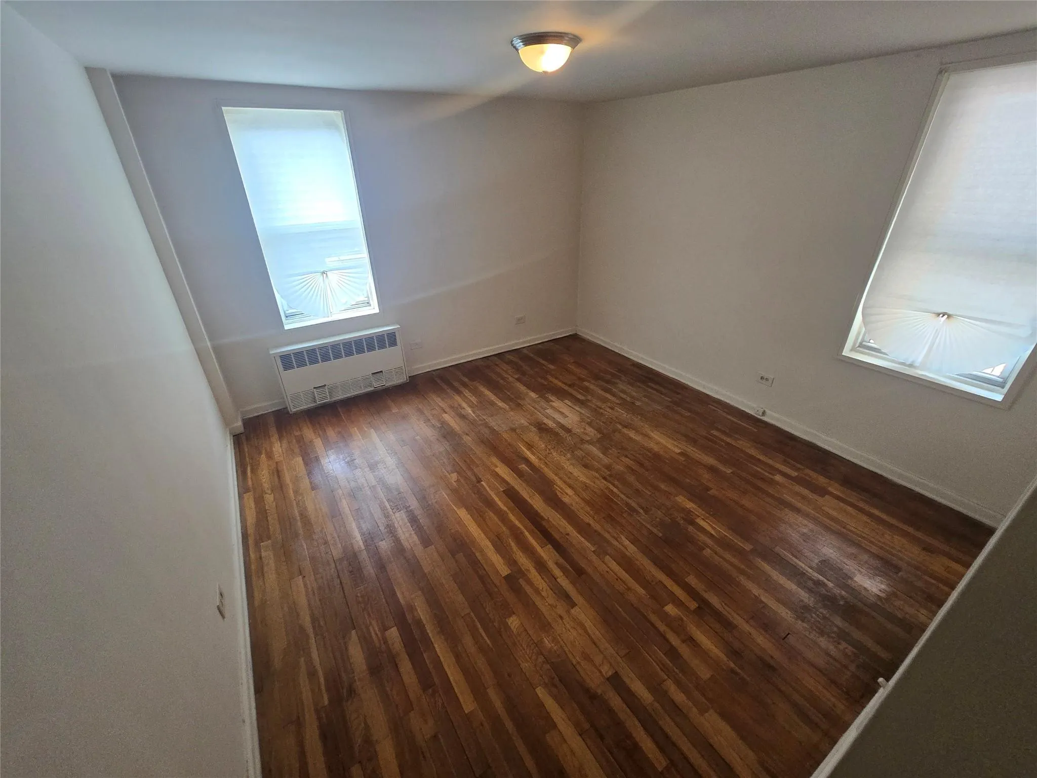 Empty room featuring radiator, baseboards, and dark wood-style flooring Empty room featuring radiator, baseboards, and dark wood-style flooring