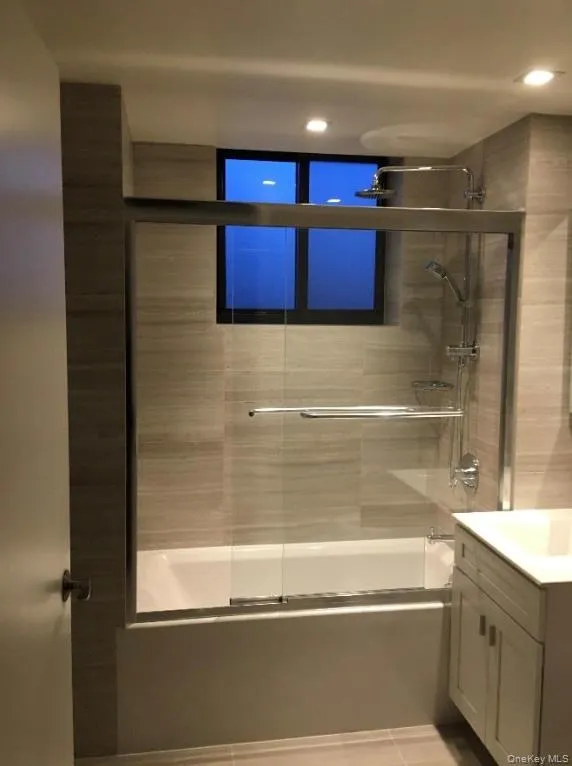 Bathroom with shower / bath combination with glass door, recessed lighting, and vanity Bathroom with shower / bath combination with glass door, recessed lighting, and vanity