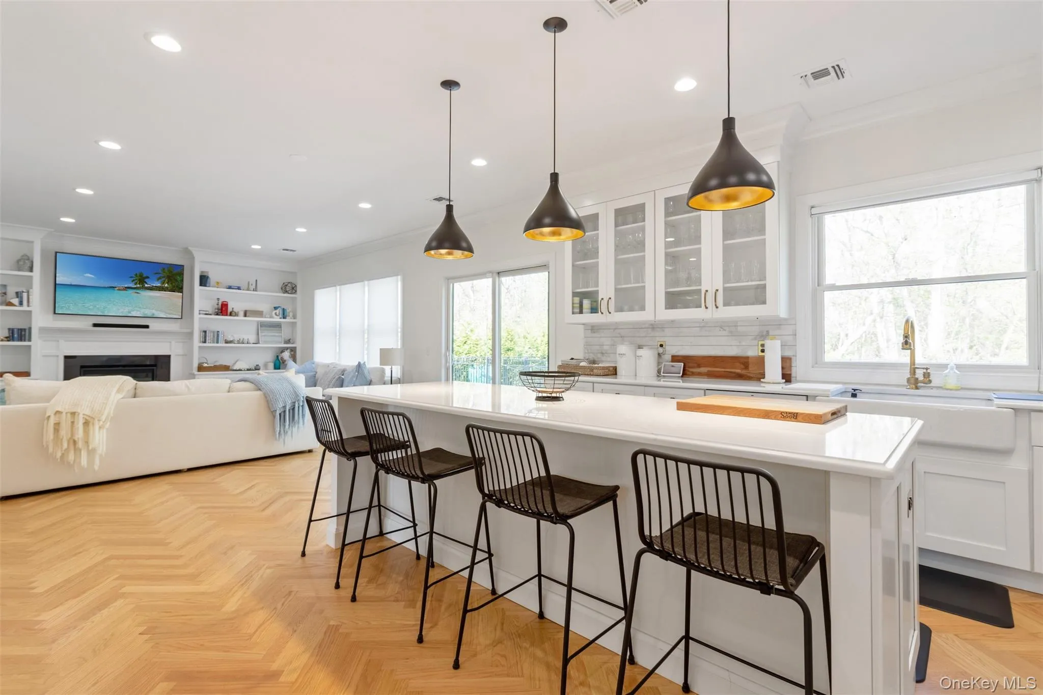 Kitchen featuring ornamental molding, a center island, light countertops, white cabinetry, and a sink Kitchen featuring ornamental molding, a center island, light countertops, white cabinetry, and a sink
