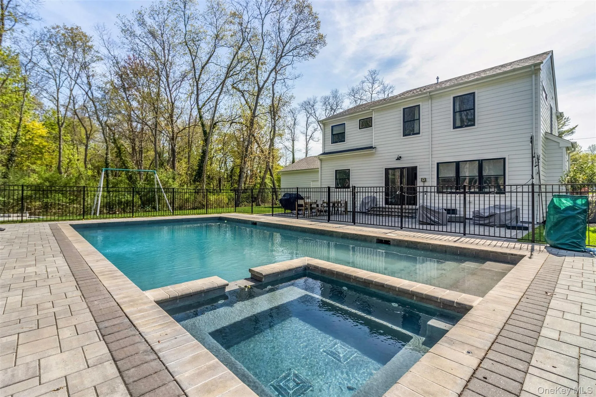 View of swimming pool with a patio area, a pool with connected hot tub, and fence View of swimming pool with a patio area, a pool with connected hot tub, and fence