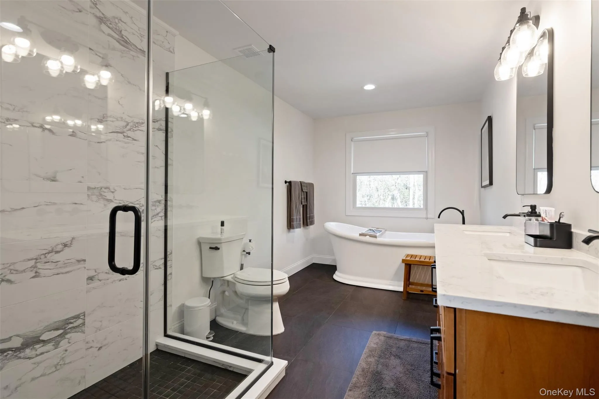 Bathroom featuring a sink, a stall shower, toilet, and a freestanding bath Bathroom featuring a sink, a stall shower, toilet, and a freestanding bath