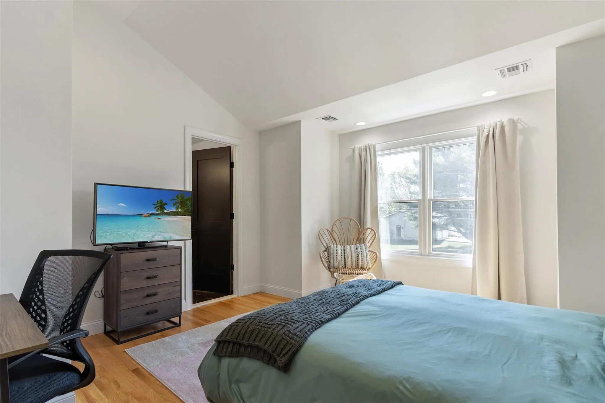 Bedroom featuring baseboards, visible vents, lofted ceiling, and light wood-style floors Bedroom featuring baseboards, visible vents, lofted ceiling, and light wood-style floors