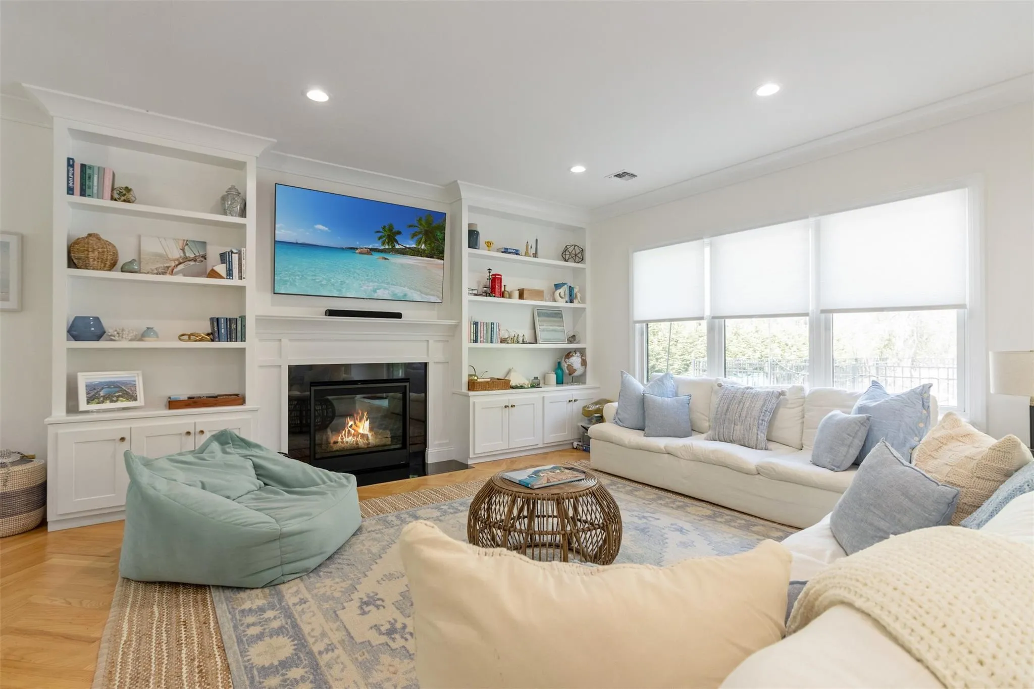 Living area featuring visible vents, a fireplace with flush hearth, built in features, ornamental molding, and recessed lighting Living area featuring visible vents, a fireplace with flush hearth, built in features, ornamental molding, and recessed lighting
