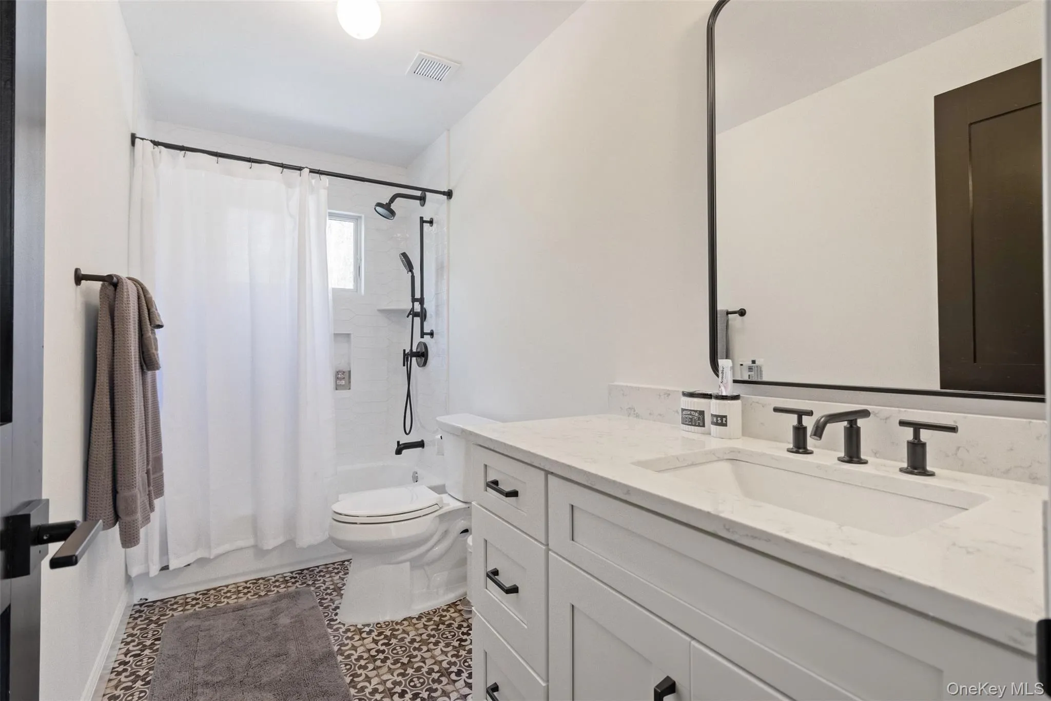 Full bath with vanity, shower / bath combo with shower curtain, toilet, and visible vents Full bath with vanity, shower / bath combo with shower curtain, toilet, and visible vents