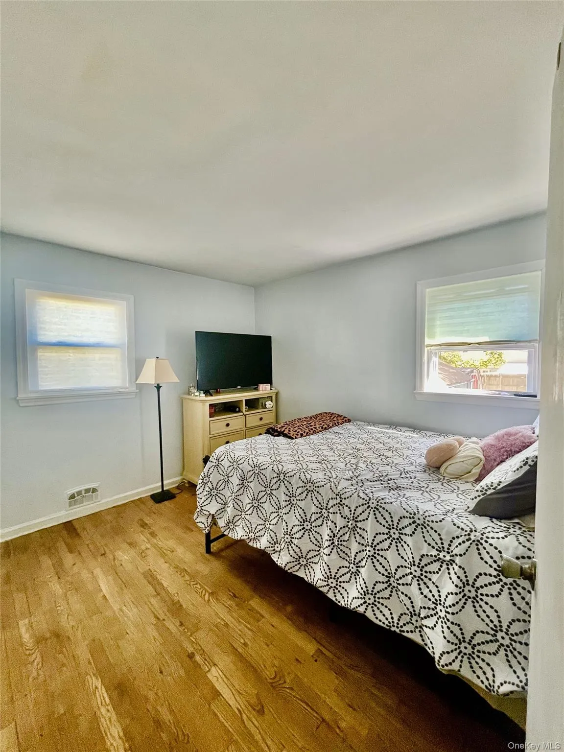 Bedroom featuring visible vents, baseboards, and wood finished floors Bedroom featuring visible vents, baseboards, and wood finished floors