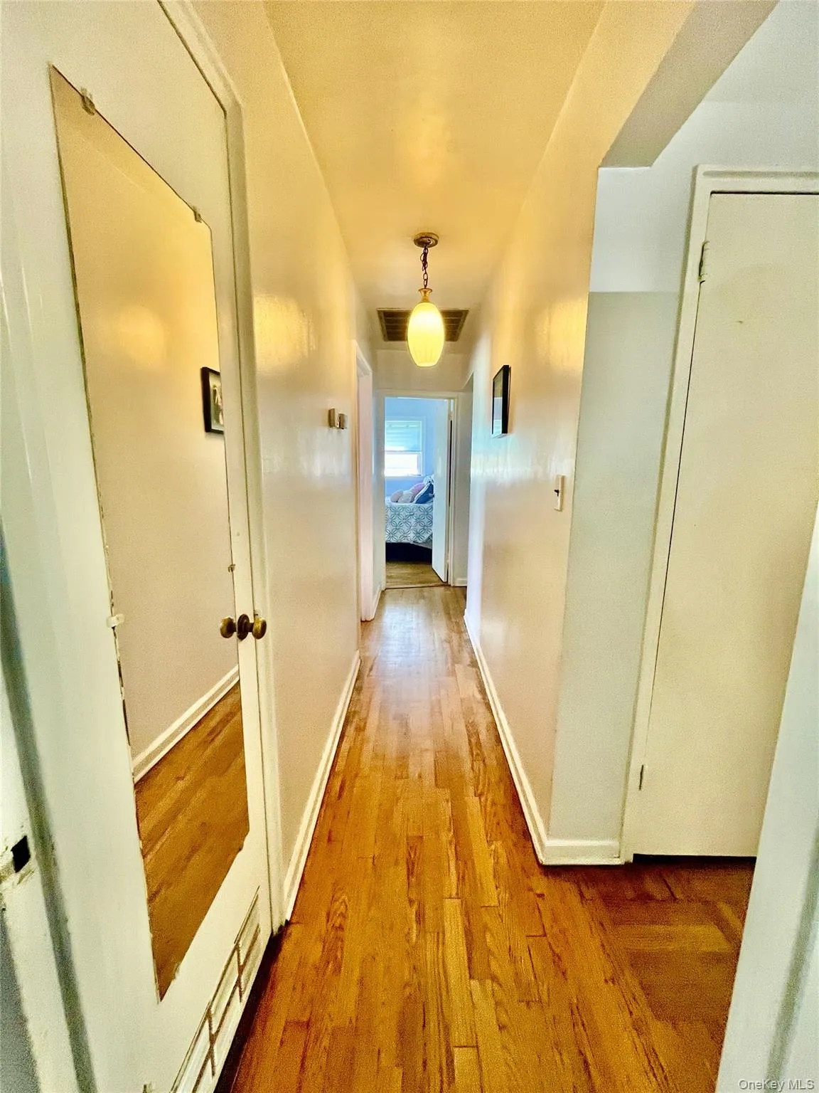 Hallway with visible vents, baseboards, and wood finished floors Hallway with visible vents, baseboards, and wood finished floors