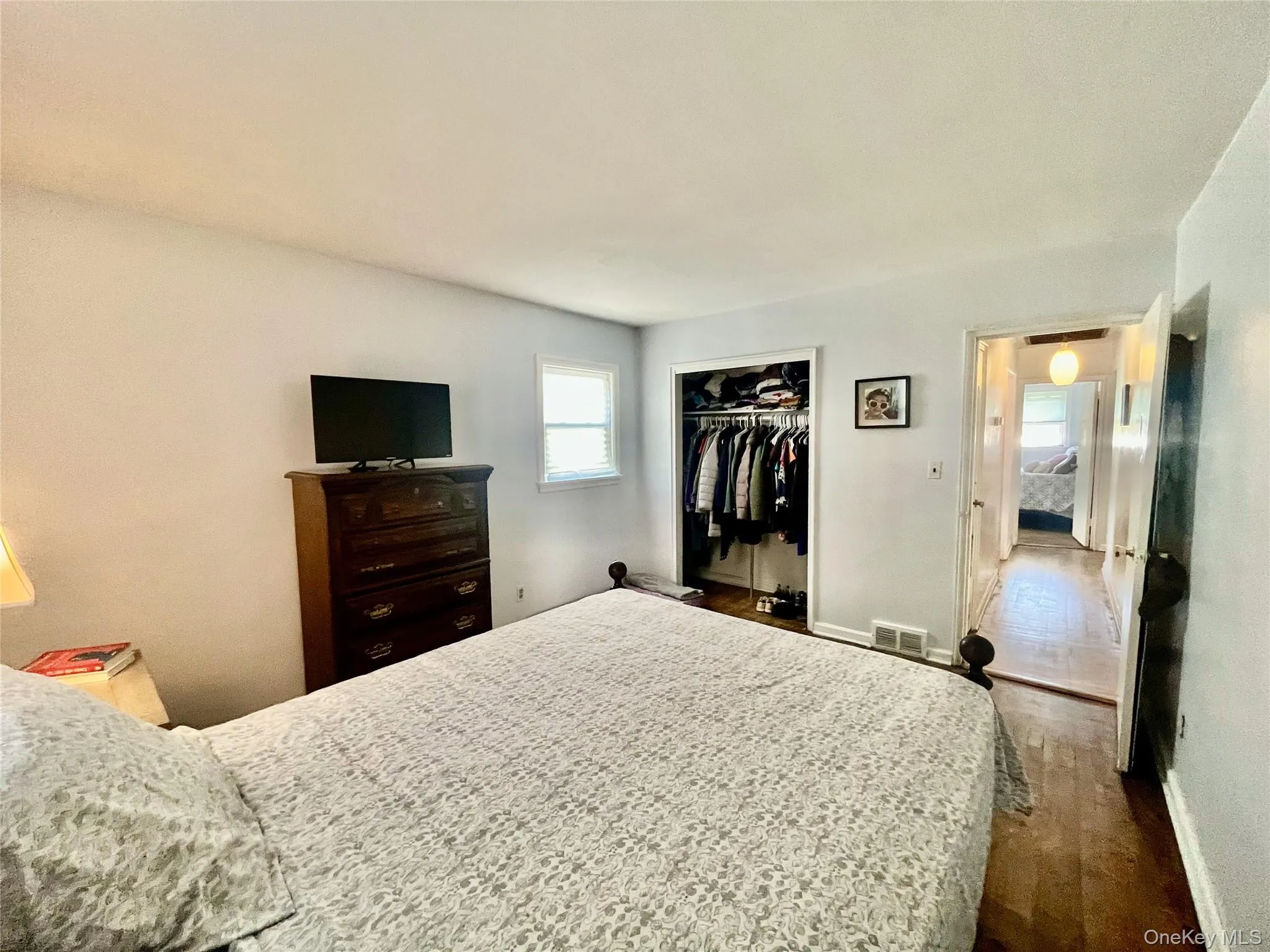 Bedroom with baseboards, visible vents, wood finished floors, and a closet Bedroom with baseboards, visible vents, wood finished floors, and a closet