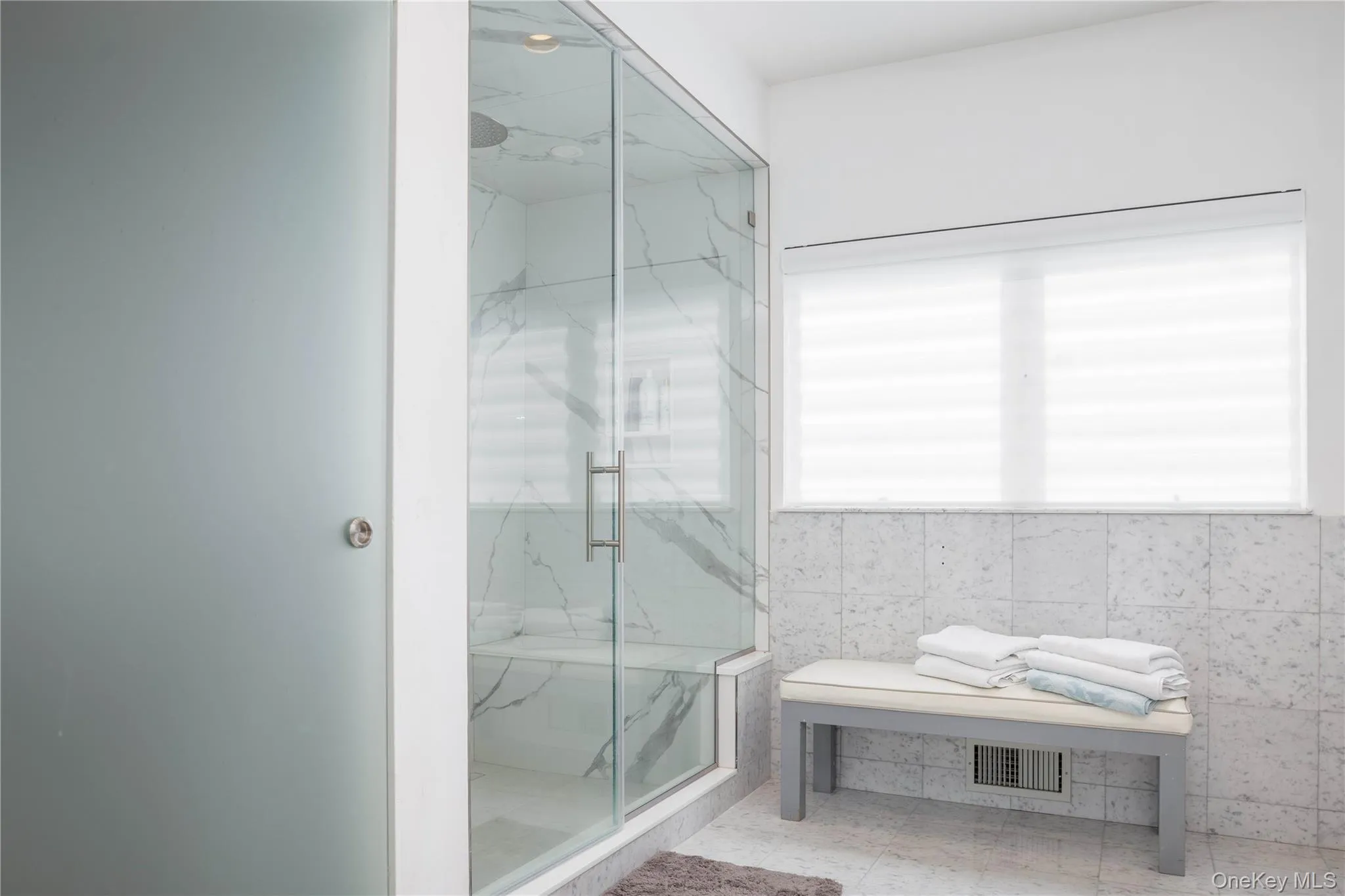 Full bathroom featuring a marble finish shower, a wealth of natural light, and visible vents Full bathroom featuring a marble finish shower, a wealth of natural light, and visible vents