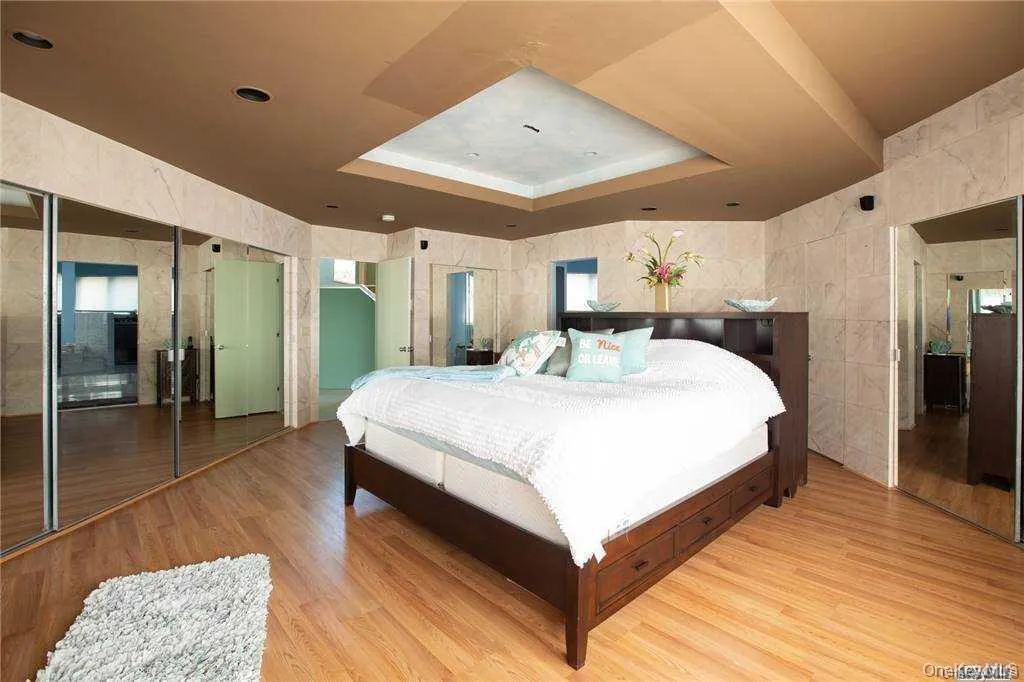 Bedroom featuring a tray ceiling, tile walls, and wood finished floors Bedroom featuring a tray ceiling, tile walls, and wood finished floors