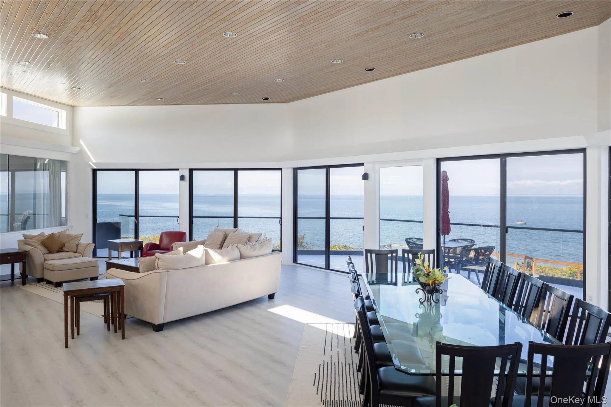 Dining room featuring a water view, light wood-style flooring, and a towering ceiling Dining room featuring a water view, light wood-style flooring, and a towering ceiling