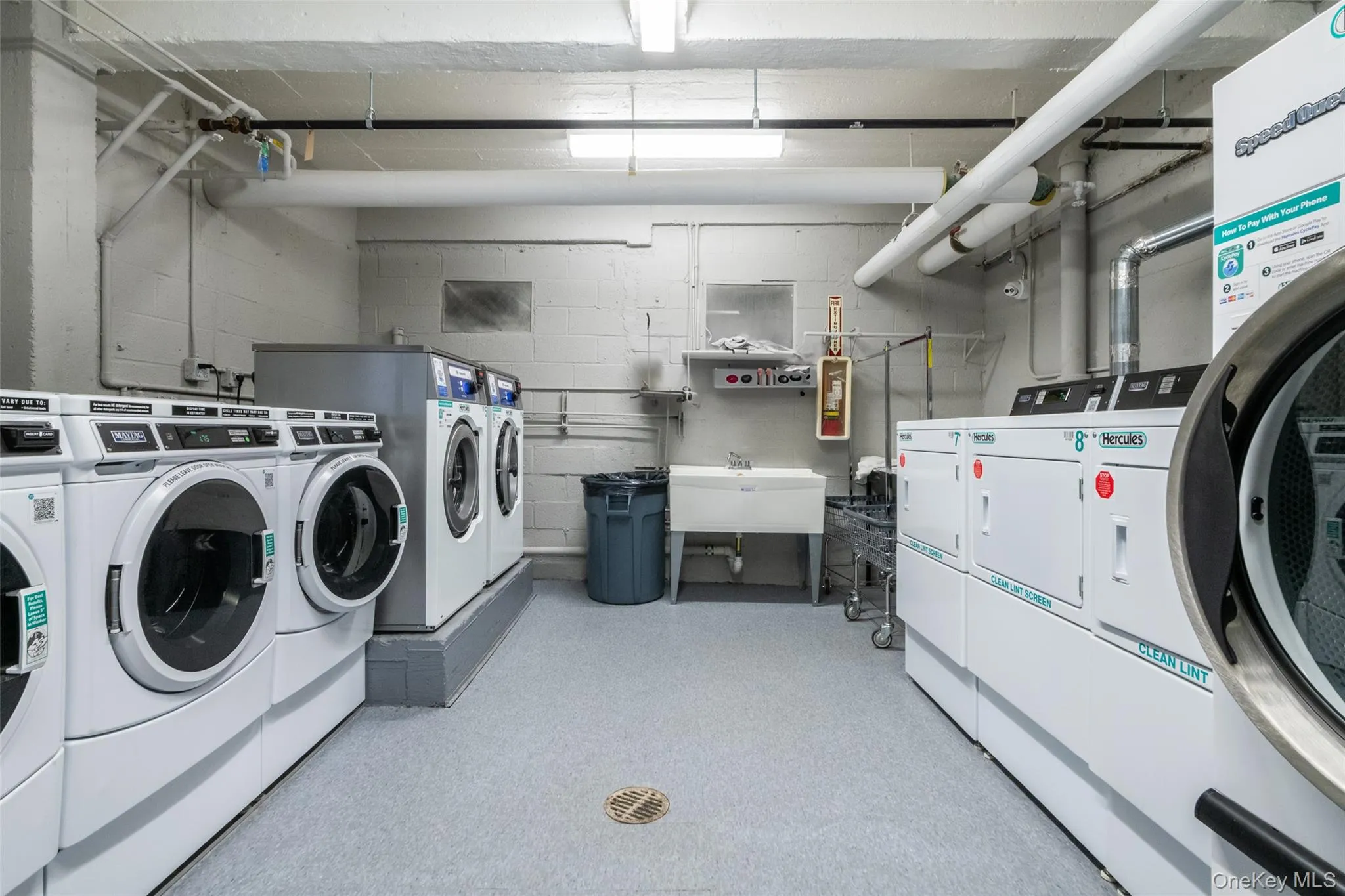 Community laundry room with washer and dryer and concrete block wall Community laundry room with washer and dryer and concrete block wall
