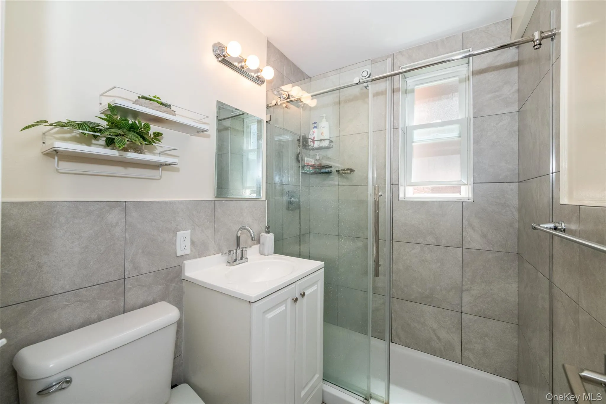 Full bathroom featuring toilet, a shower stall, vanity, and tile walls Full bathroom featuring toilet, a shower stall, vanity, and tile walls