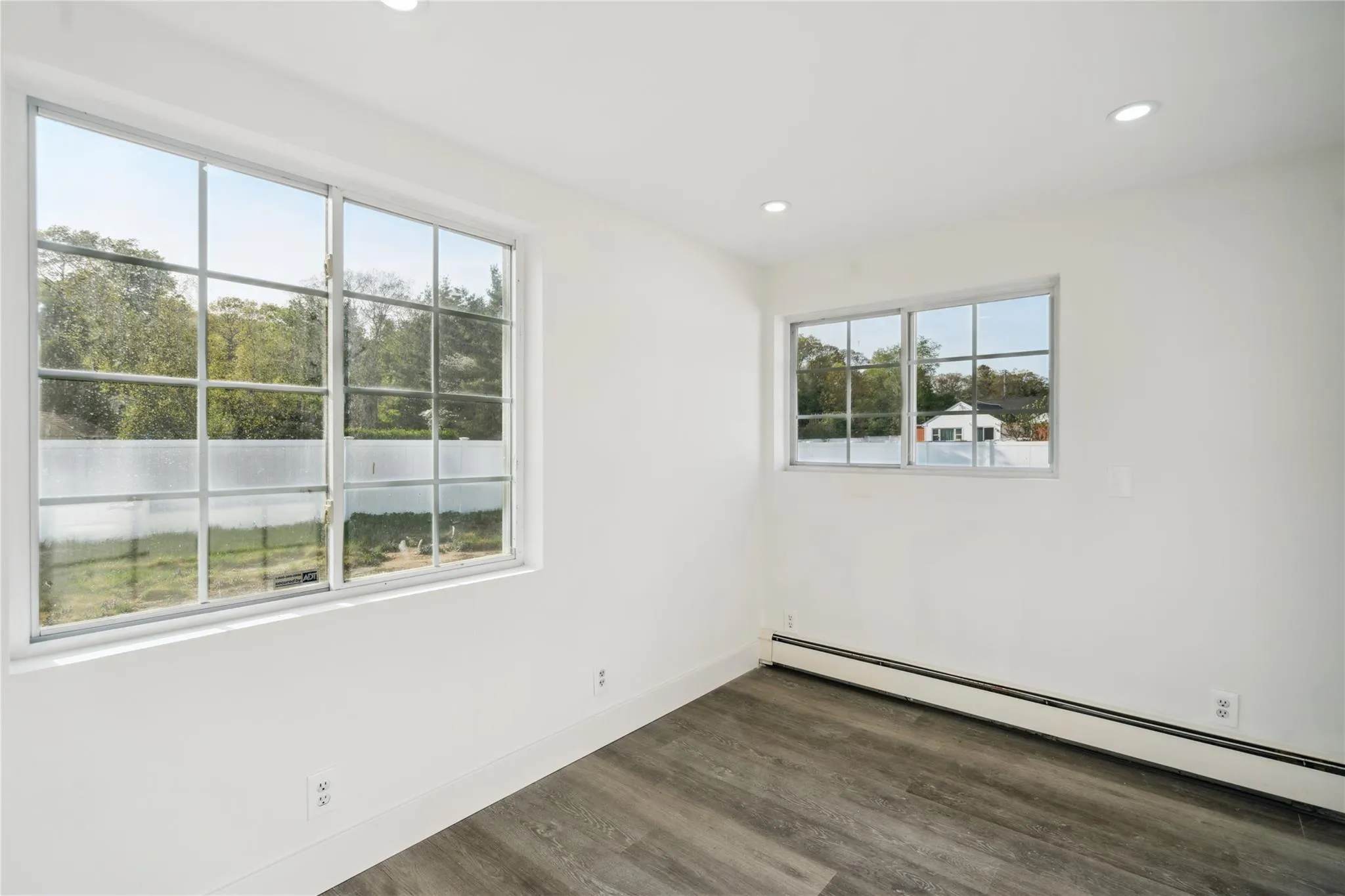Empty room with plenty of natural light, wood finished floors, baseboard heating, and recessed lighting Empty room with plenty of natural light, wood finished floors, baseboard heating, and recessed lighting
