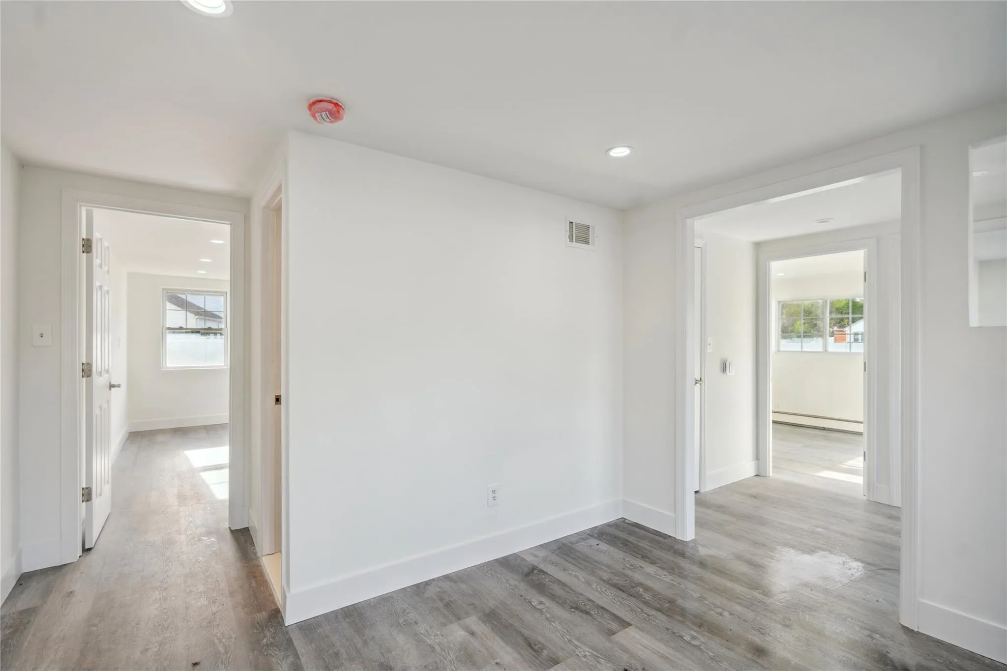 Empty room featuring baseboards, a baseboard radiator, a healthy amount of sunlight, and wood finished floors Empty room featuring baseboards, a baseboard radiator, a healthy amount of sunlight, and wood finished floors
