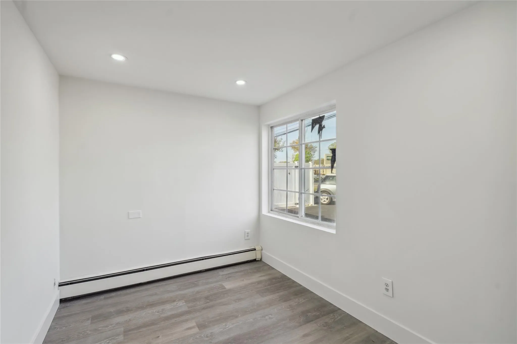 Empty room featuring wood finished floors, baseboards, baseboard heating, and recessed lighting Empty room featuring wood finished floors, baseboards, baseboard heating, and recessed lighting