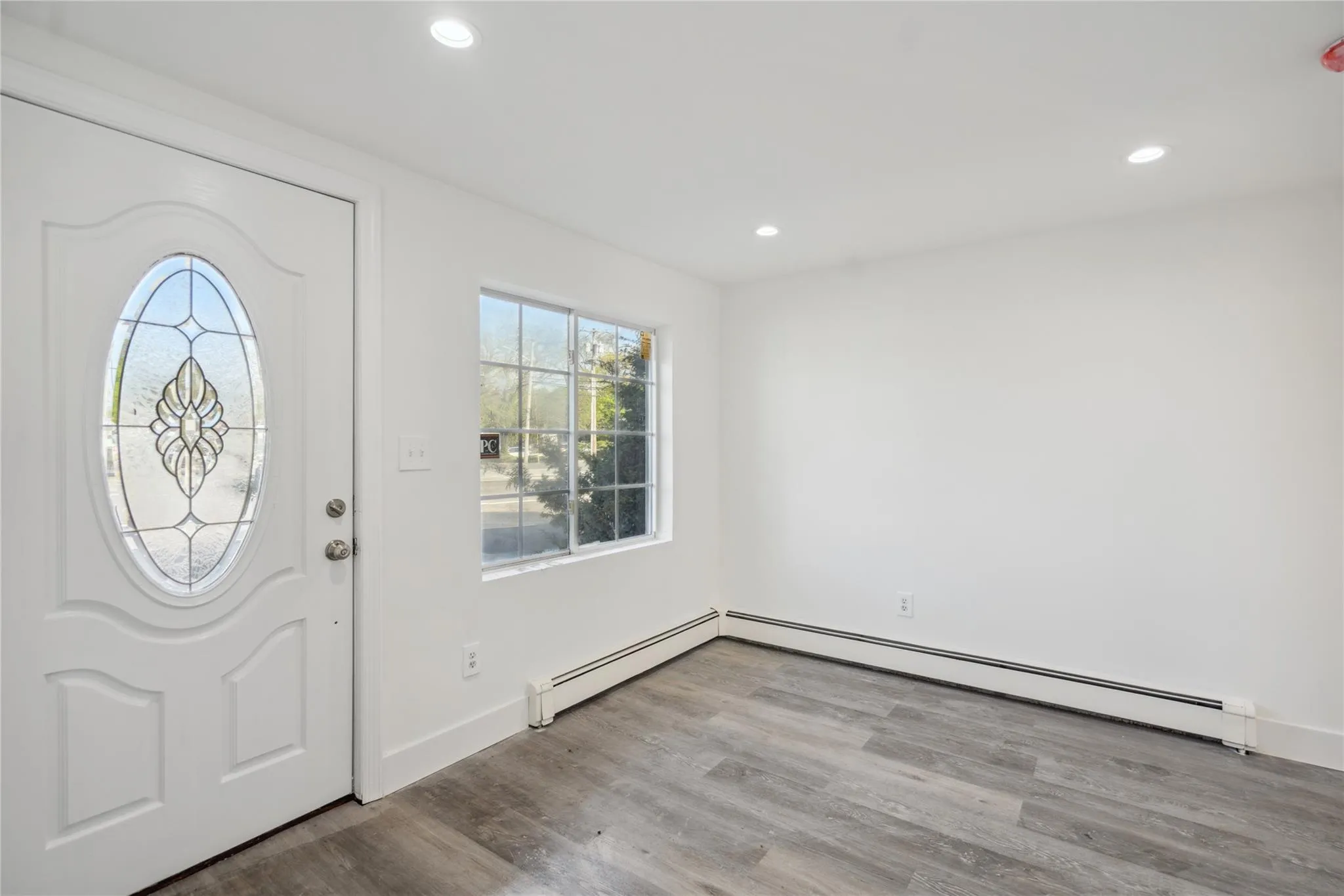 Foyer entrance with wood finished floors, baseboards, a baseboard heating unit, and recessed lighting Foyer entrance with wood finished floors, baseboards, a baseboard heating unit, and recessed lighting