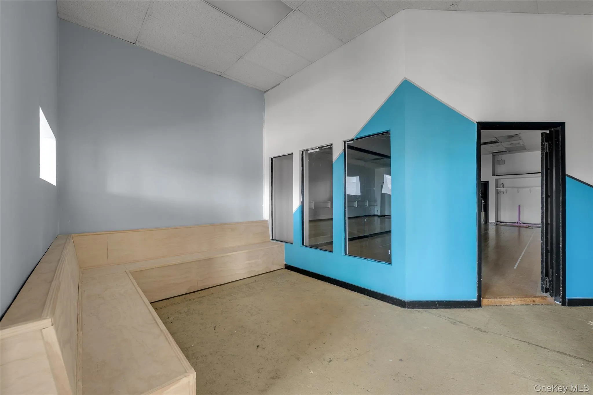 Empty room featuring unfinished concrete flooring, a paneled ceiling, and a high ceiling Empty room featuring unfinished concrete flooring, a paneled ceiling, and a high ceiling