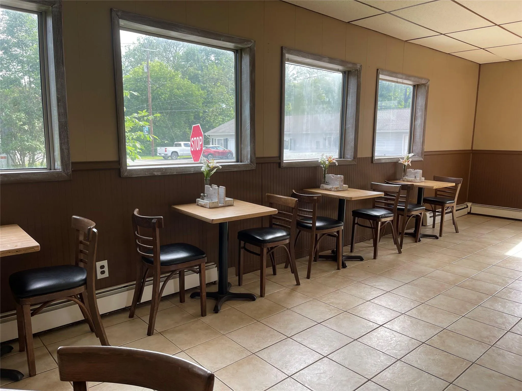 Dining area with a wainscoted wall, light tile patterned floors, wood walls, and a baseboard radiator Dining area with a wainscoted wall, light tile patterned floors, wood walls, and a baseboard radiator