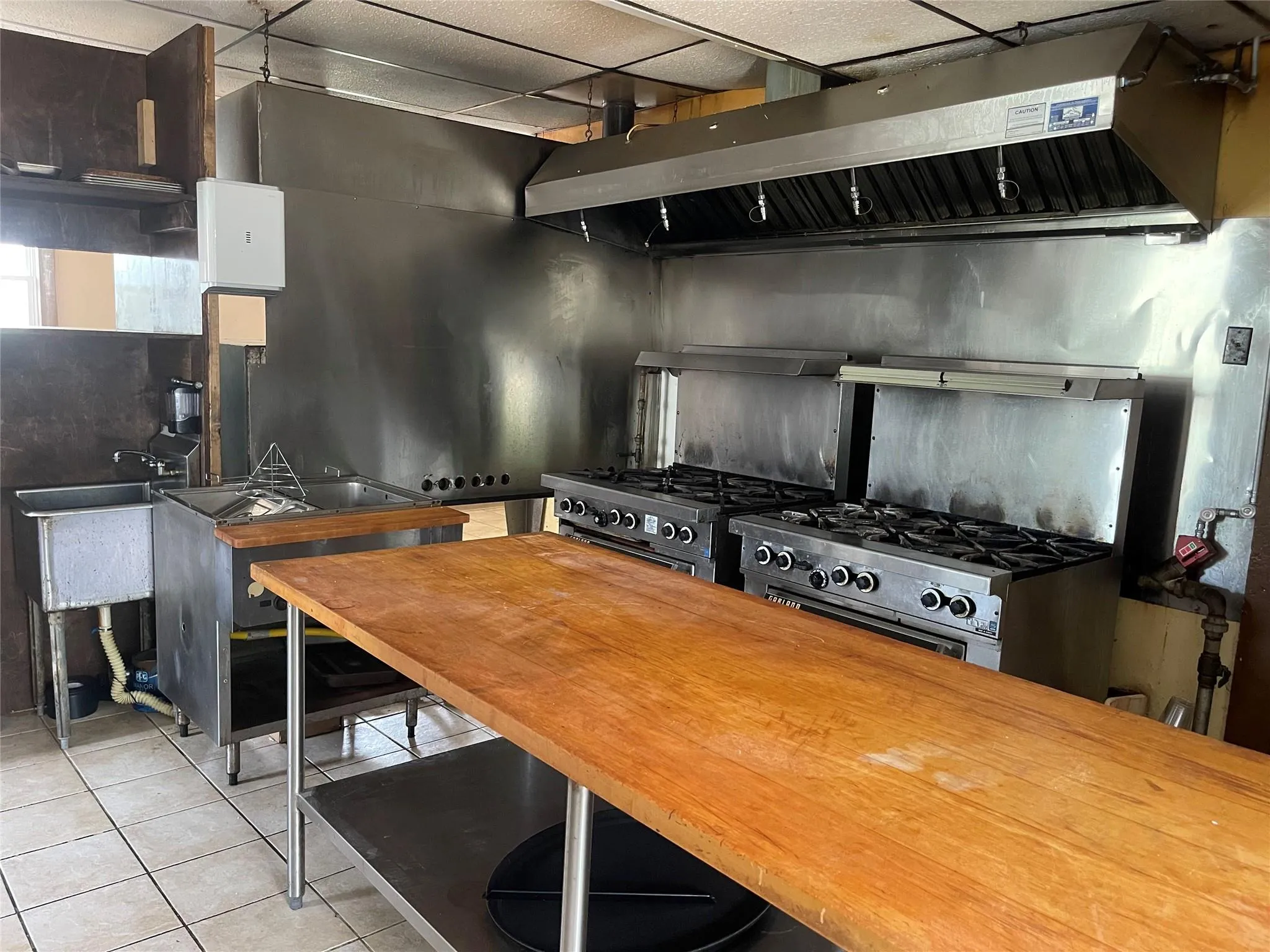 Kitchen with tile patterned floors, ventilation hood, and range with gas stovetop Kitchen with tile patterned floors, ventilation hood, and range with gas stovetop