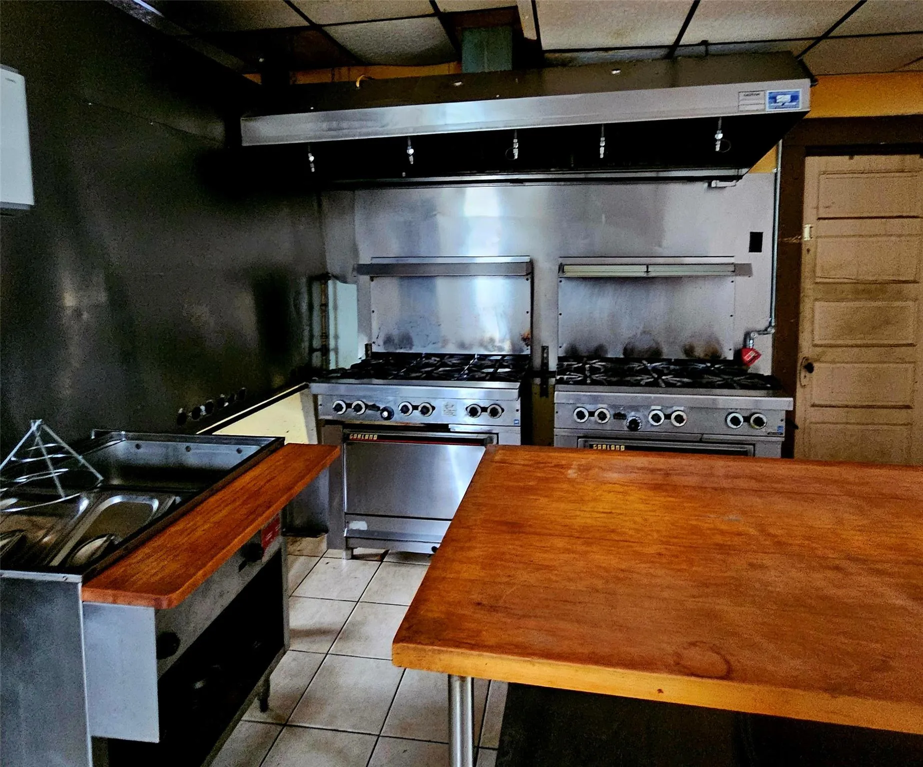 Kitchen featuring wood counters, tile patterned floors, and stainless steel stove Kitchen featuring wood counters, tile patterned floors, and stainless steel stove