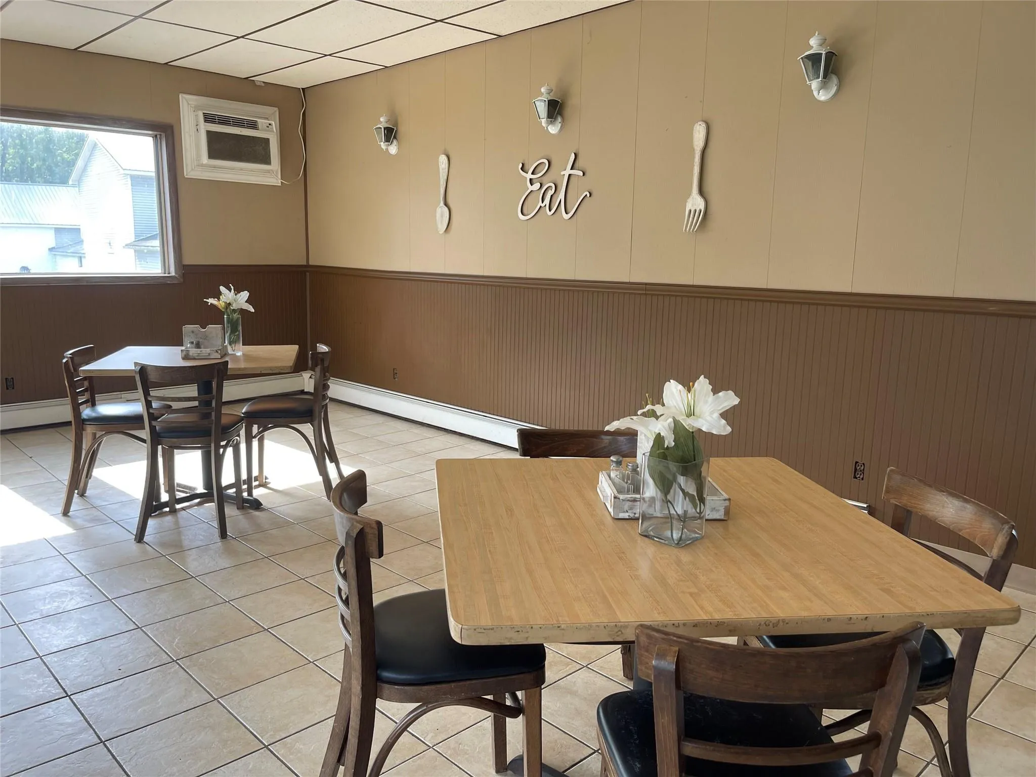 Dining space featuring a wall unit AC, a wainscoted wall, light tile patterned floors, and baseboard heating Dining space featuring a wall unit AC, a wainscoted wall, light tile patterned floors, and baseboard heating