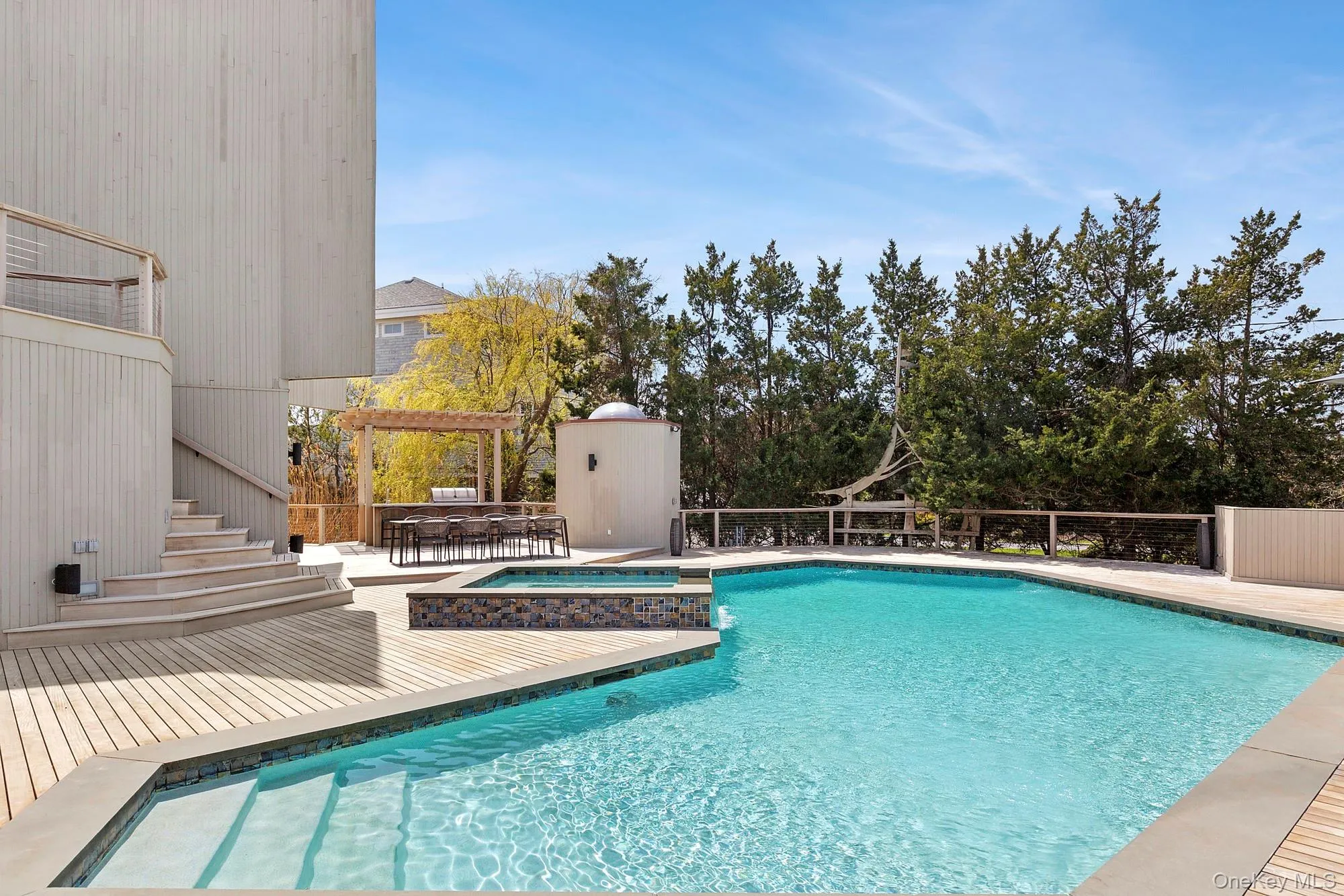 View of swimming pool featuring a pool with connected hot tub, a pergola, a wooden deck, and outdoor dining space