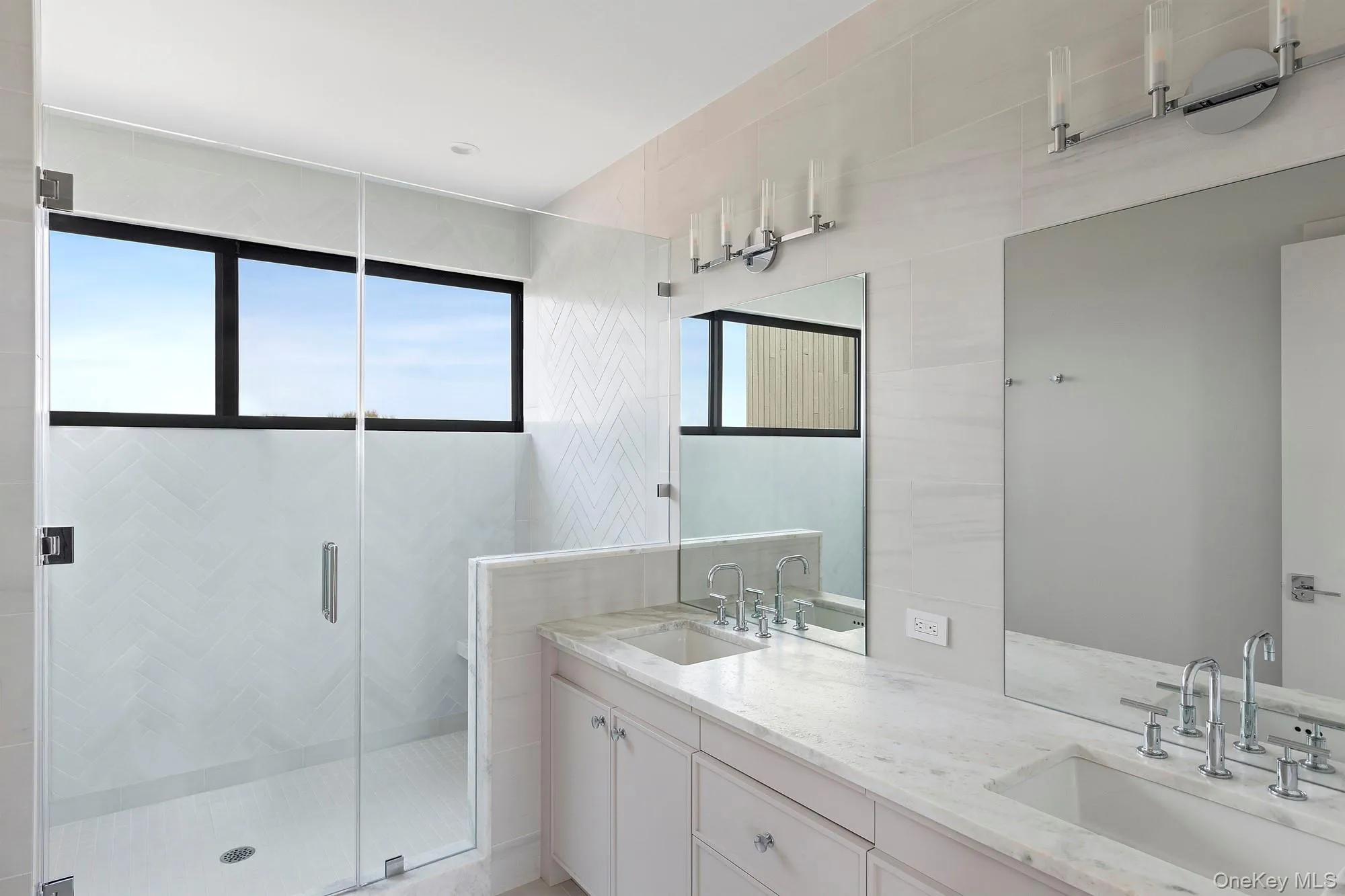 Full bathroom with double vanity, a stall shower, and a sink
