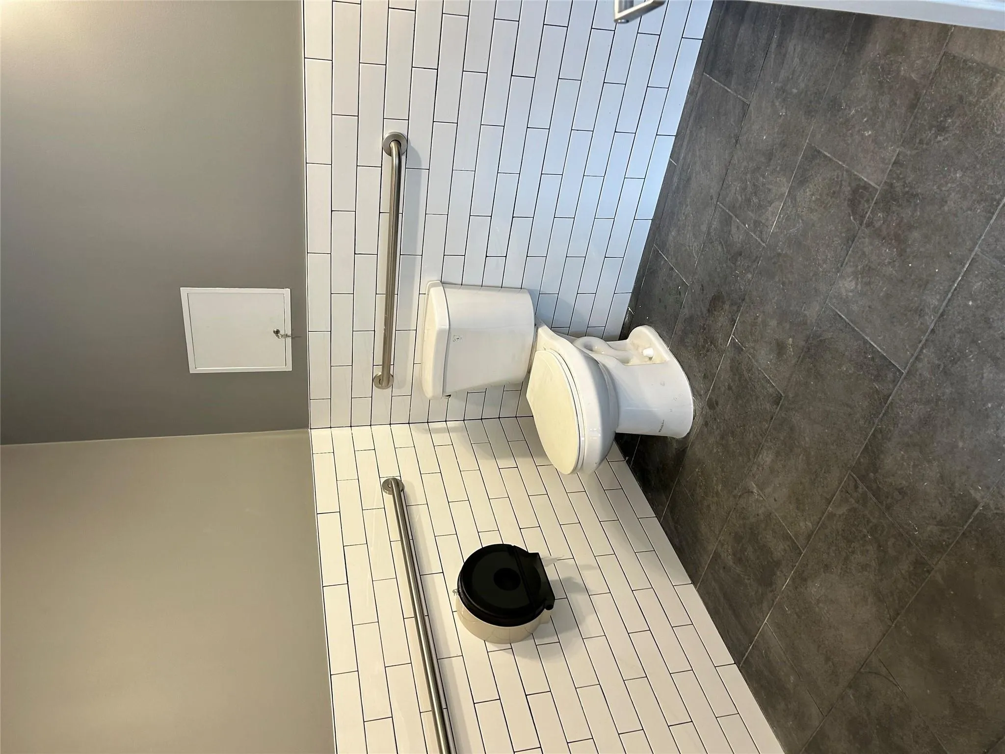 Half bath with wainscoting, tile walls, toilet, and stone finish floor Half bath with wainscoting, tile walls, toilet, and stone finish floor