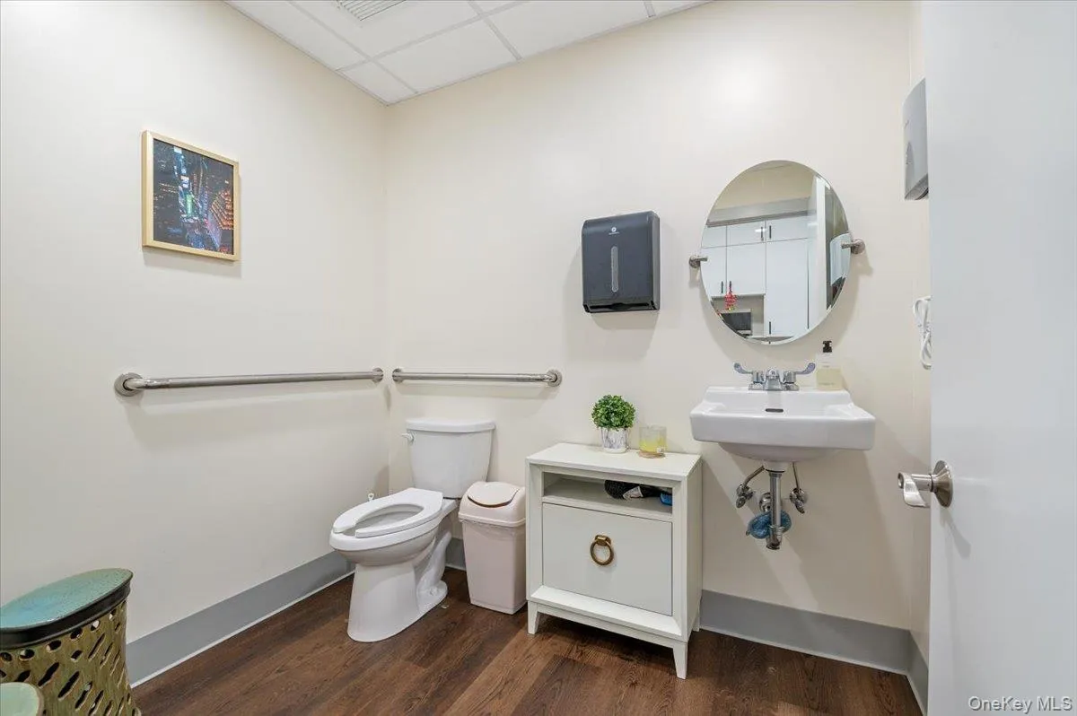 Half bath featuring toilet, a drop ceiling, wood finished floors, and baseboards Half bath featuring toilet, a drop ceiling, wood finished floors, and baseboards