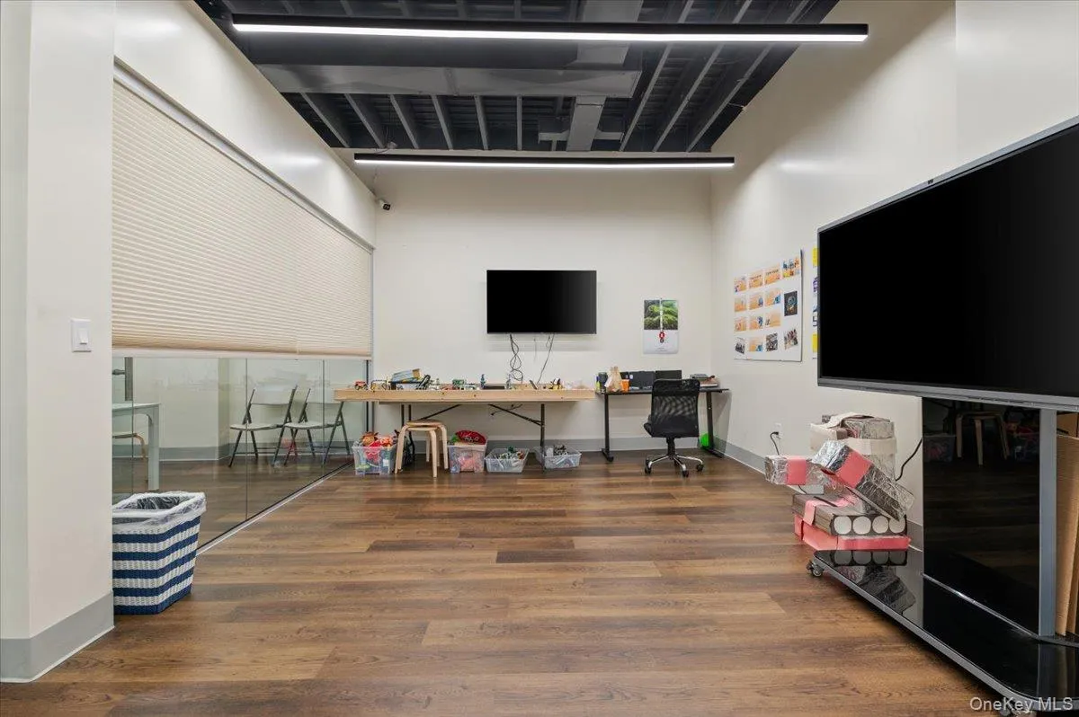 Playroom featuring wood finished floors, baseboards, and a towering ceiling Playroom featuring wood finished floors, baseboards, and a towering ceiling