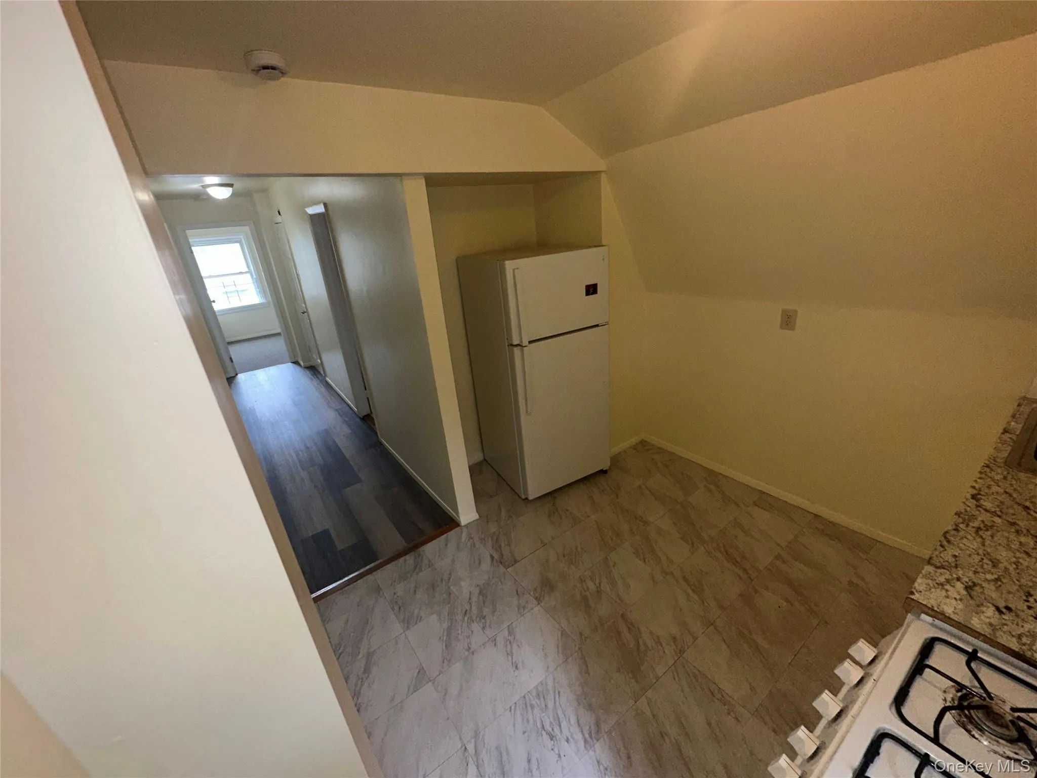 Kitchen featuring freestanding refrigerator, baseboards, and vaulted ceiling Kitchen featuring freestanding refrigerator, baseboards, and vaulted ceiling