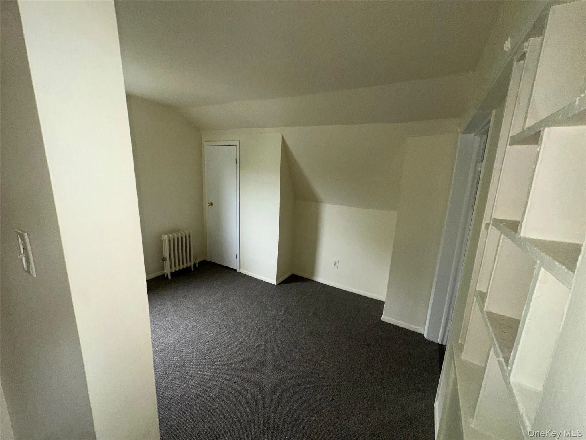 Bonus room featuring dark carpet and radiator heating unit Bonus room featuring dark carpet and radiator heating unit