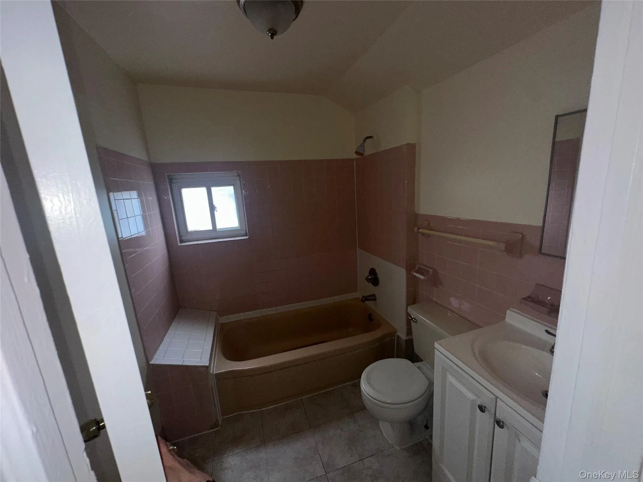 Bathroom featuring tile walls, shower / washtub combination, toilet, vanity, and tile patterned floors Bathroom featuring tile walls, shower / washtub combination, toilet, vanity, and tile patterned floors