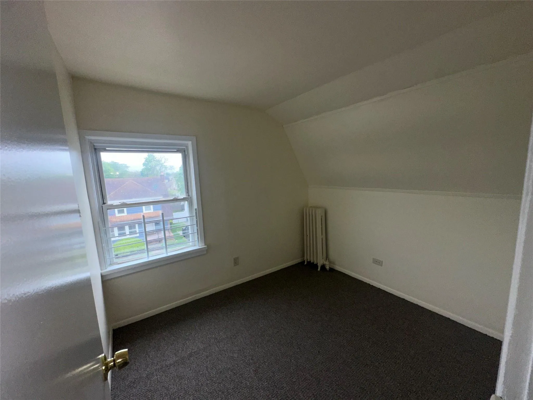 Bonus room with dark colored carpet, baseboards, lofted ceiling, and radiator heating unit Bonus room with dark colored carpet, baseboards, lofted ceiling, and radiator heating unit