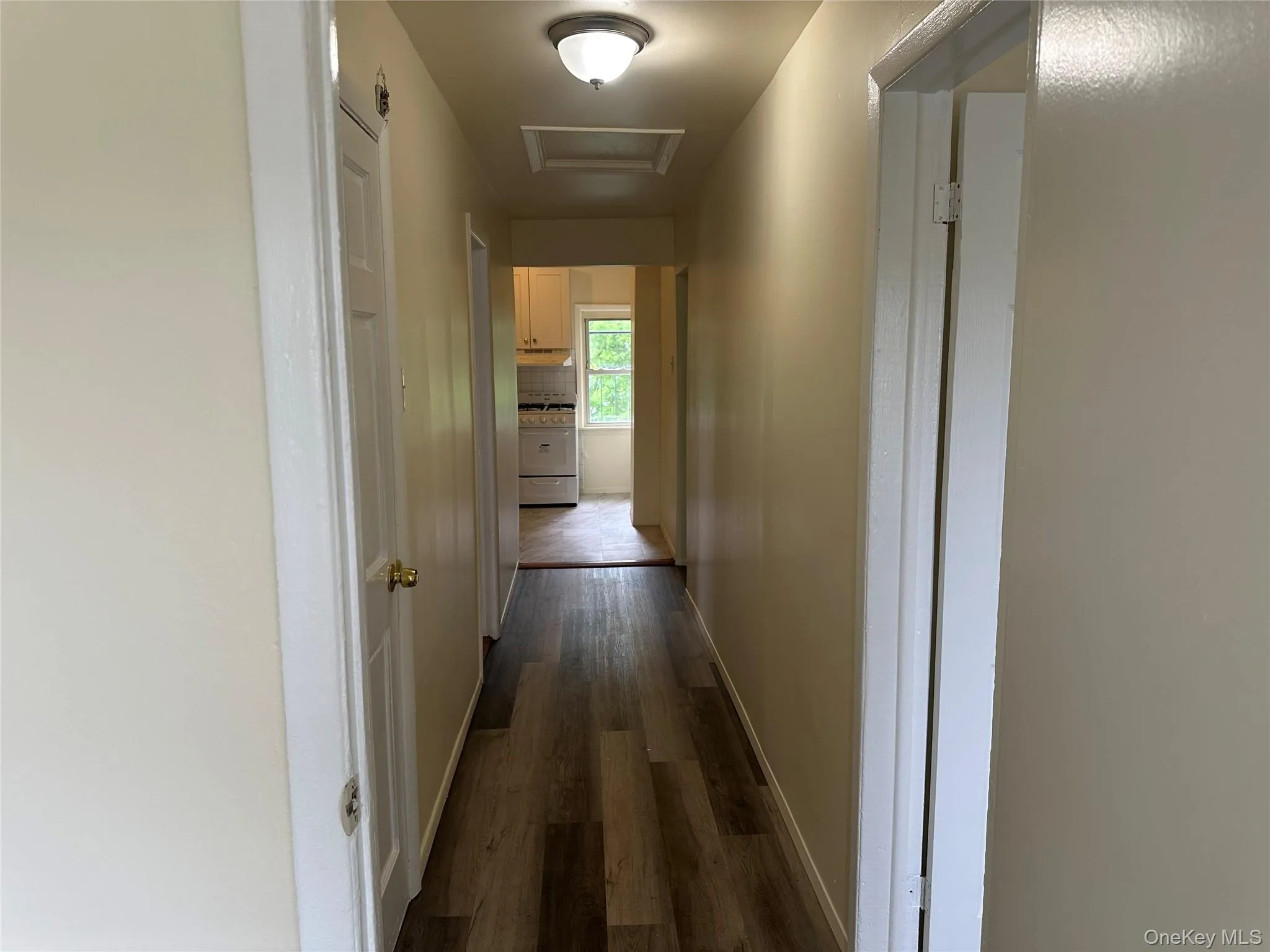 Corridor with attic access, baseboards, and dark wood finished floors Corridor with attic access, baseboards, and dark wood finished floors