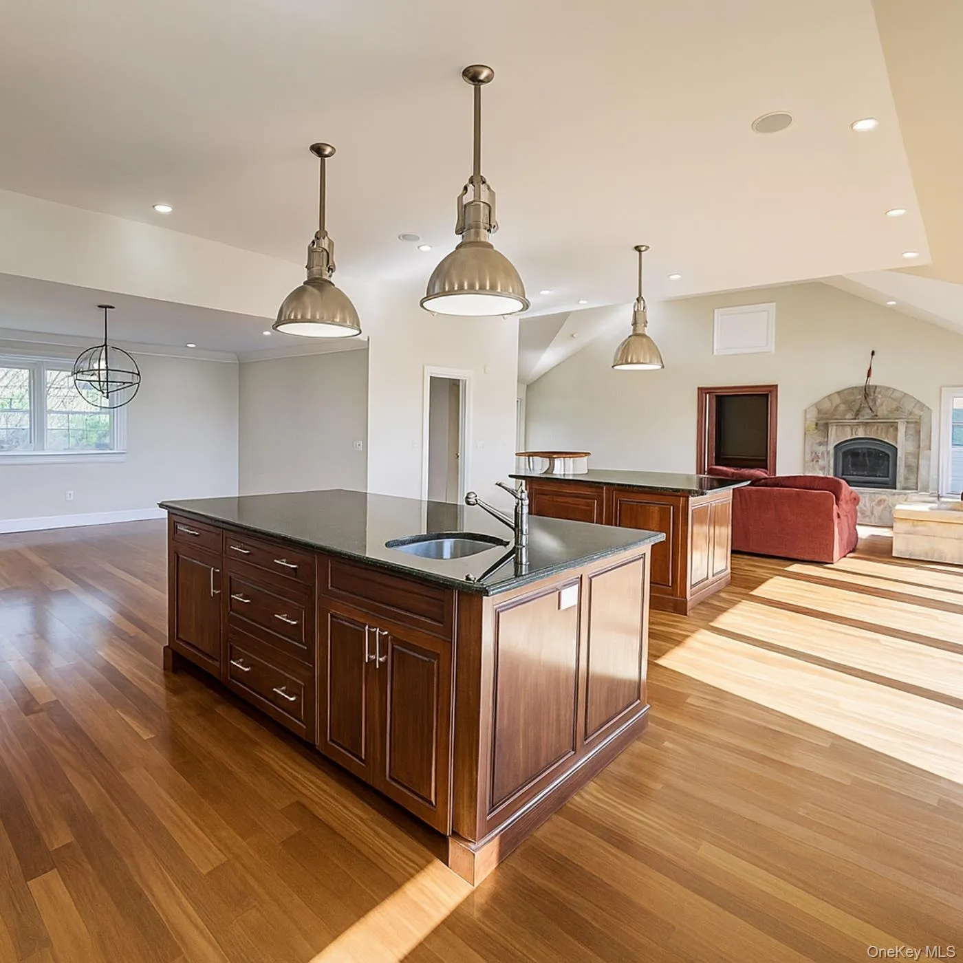 Kitchen with open floor plan, a kitchen island with sink, pendant lighting, dark stone counters, and a fireplace Kitchen with open floor plan, a kitchen island with sink, pendant lighting, dark stone counters, and a fireplace