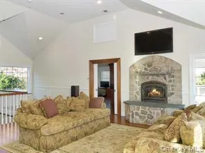 Living area featuring a stone fireplace, wood finished floors, recessed lighting, and high vaulted ceiling Living area featuring a stone fireplace, wood finished floors, recessed lighting, and high vaulted ceiling