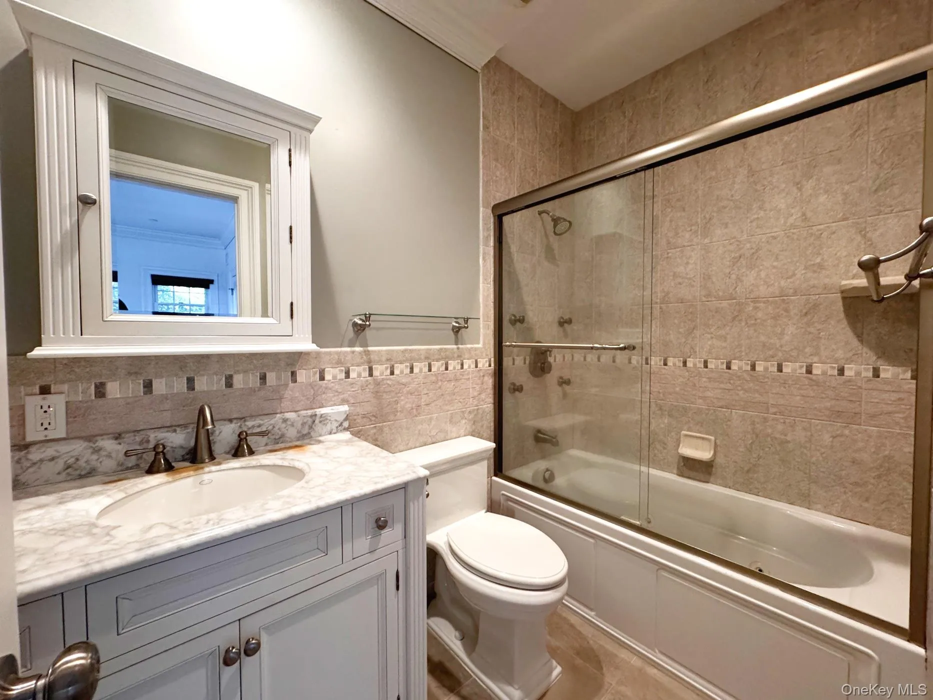 Ground floor bathroom with tile walls, shower / bath combination with glass door, and vanity Ground floor bathroom with tile walls, shower / bath combination with glass door, and vanity