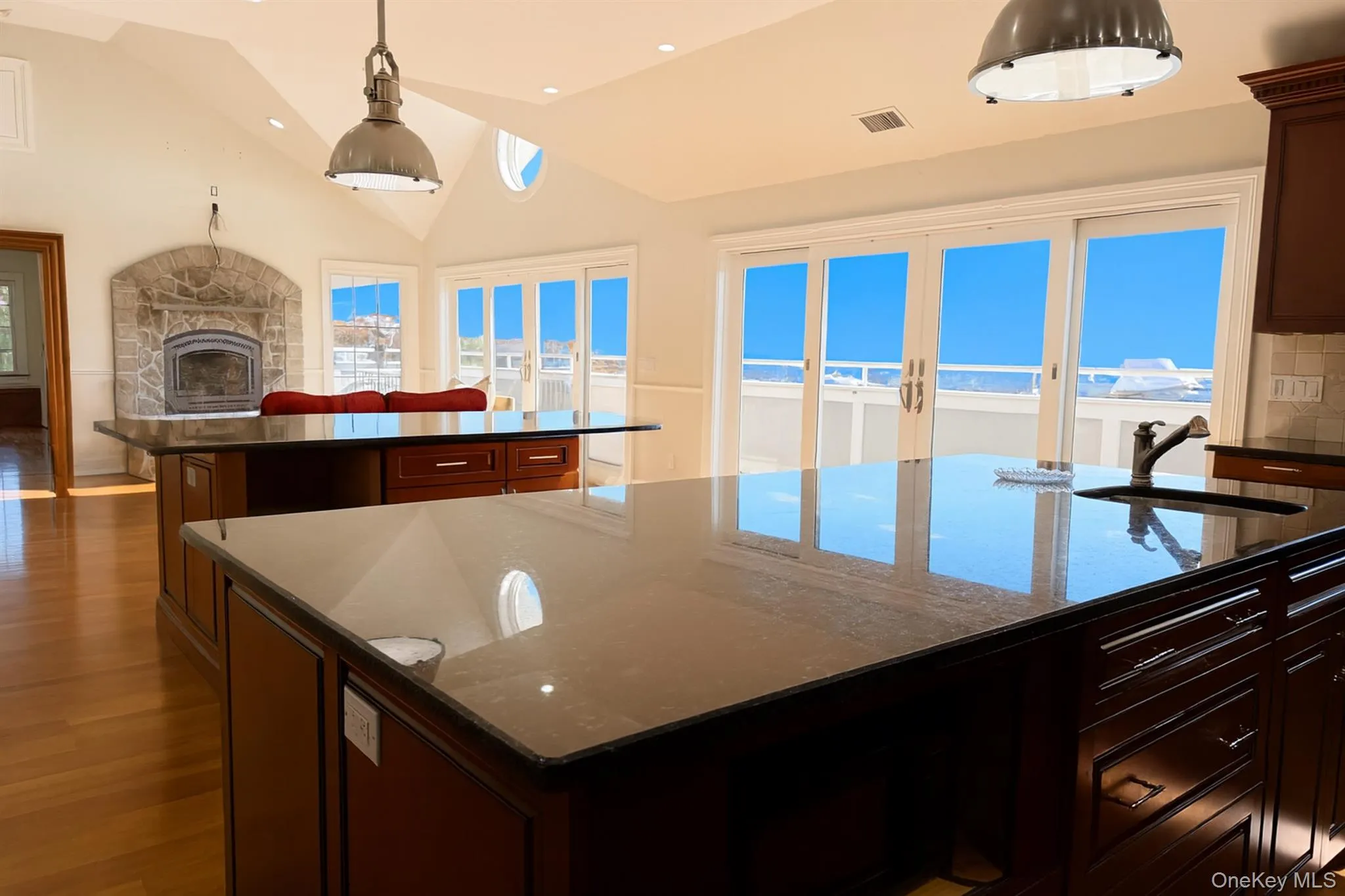 Kitchen with dark stone countertops, decorative light fixtures, a fireplace, dark wood-type flooring, and dark brown cabinetry Kitchen with dark stone countertops, decorative light fixtures, a fireplace, dark wood-type flooring, and dark brown cabinetry