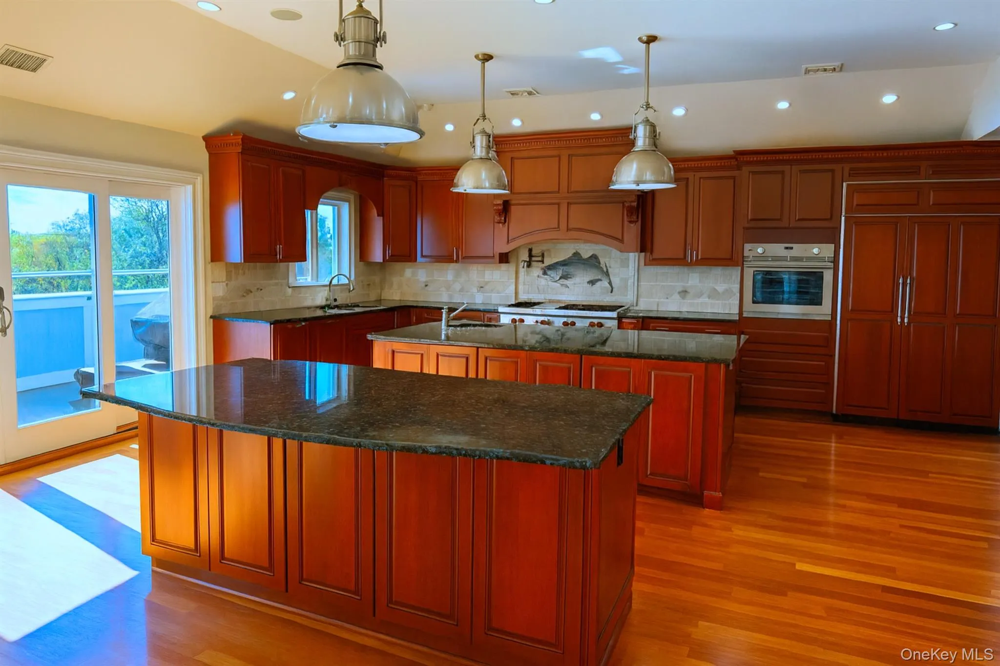 Kitchen featuring dark stone counters, paneled fridge, recessed lighting, light wood finished floors, and pendant lighting Kitchen featuring dark stone counters, paneled fridge, recessed lighting, light wood finished floors, and pendant lighting
