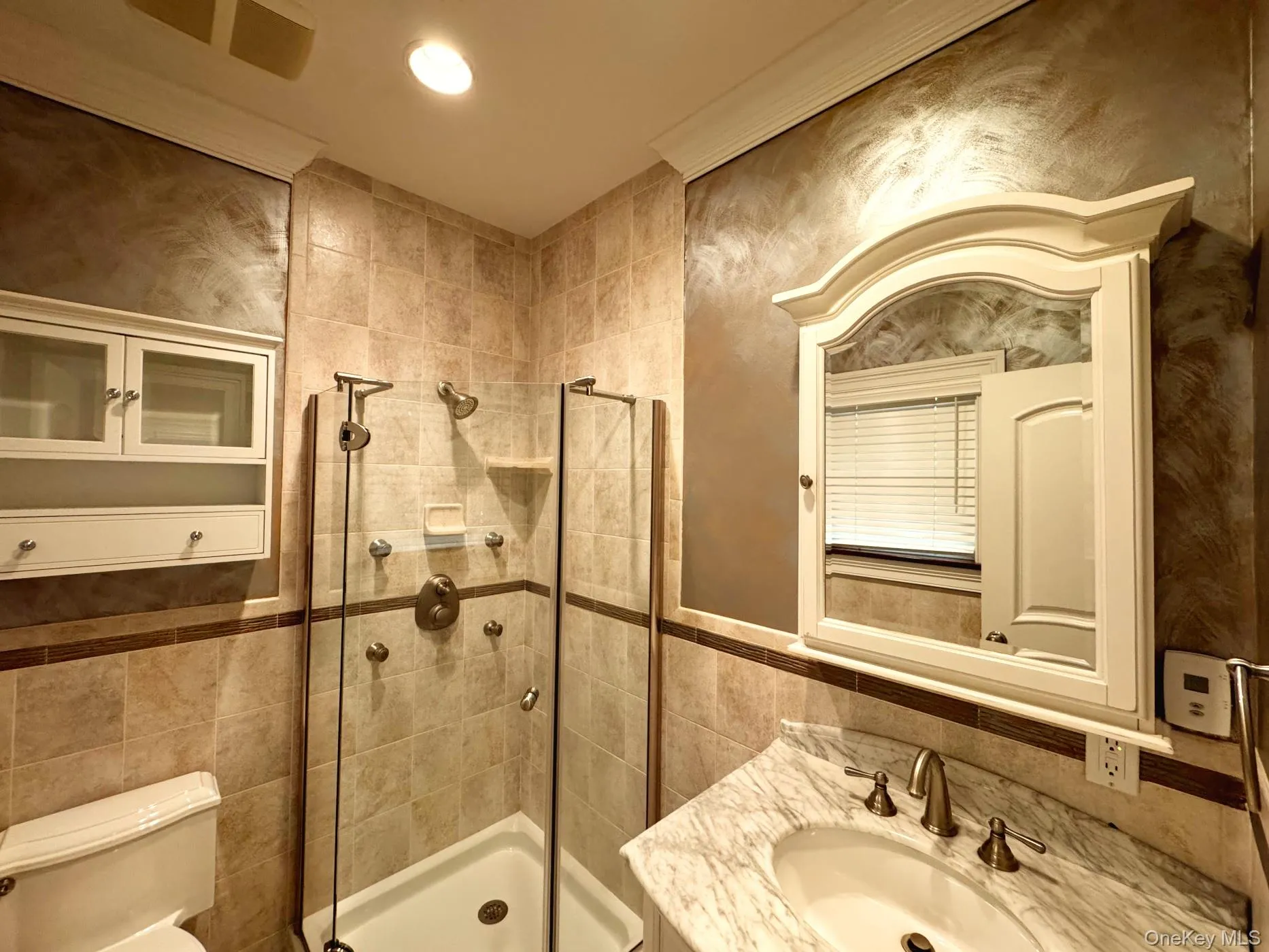 Bathroom with tile walls, vanity, a shower stall, and recessed lighting Bathroom with tile walls, vanity, a shower stall, and recessed lighting