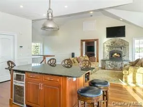 Kitchen featuring vaulted ceiling, wood finished floors, a stone fireplace, a center island, and decorative light fixtures Kitchen featuring vaulted ceiling, wood finished floors, a stone fireplace, a center island, and decorative light fixtures