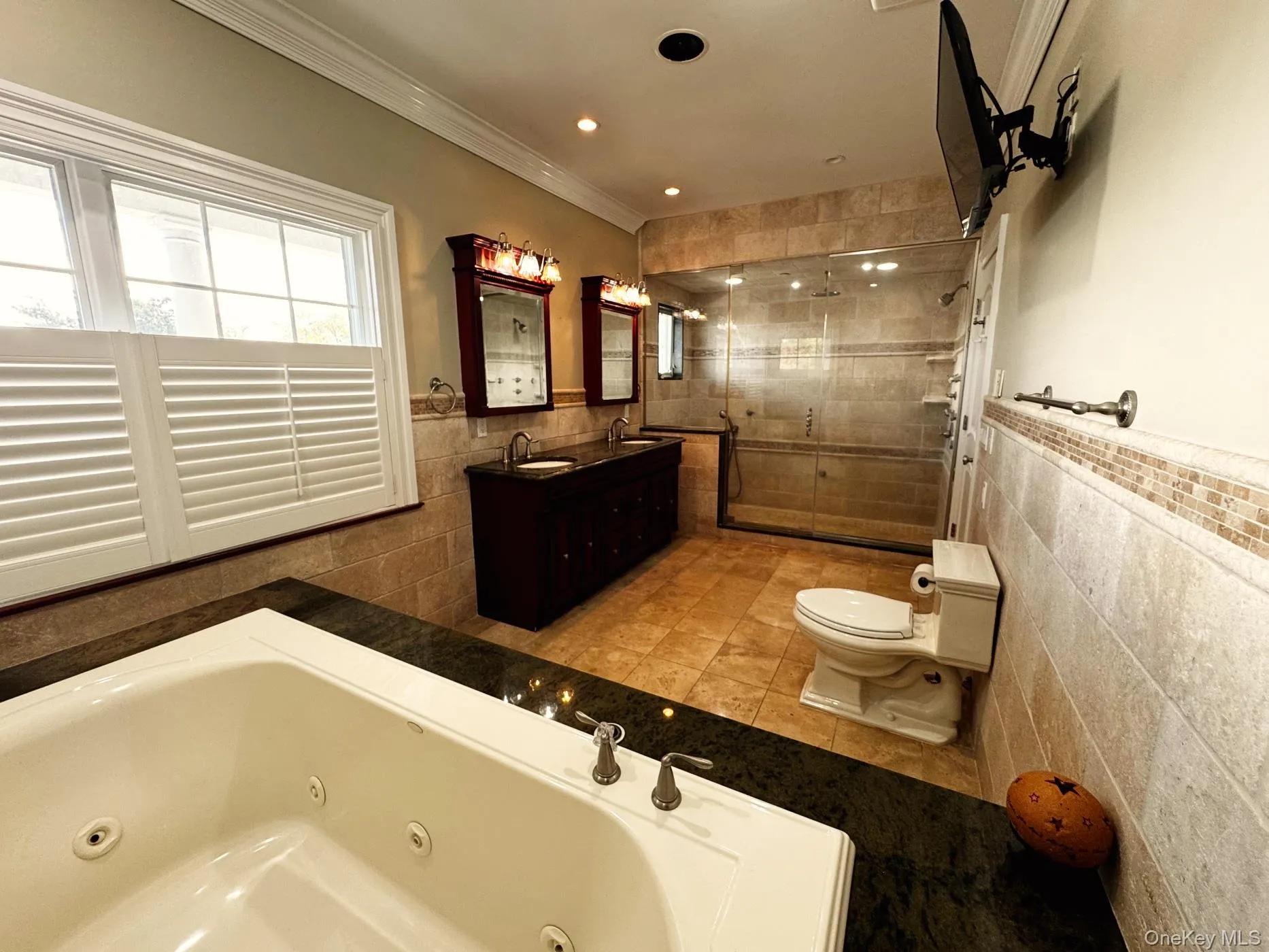 Primary Bathroom featuring tile walls, walk in steam shower, crown moldings, spa tub, and double vanity Primary Bathroom featuring tile walls, walk in steam shower, crown moldings, spa tub, and double vanity