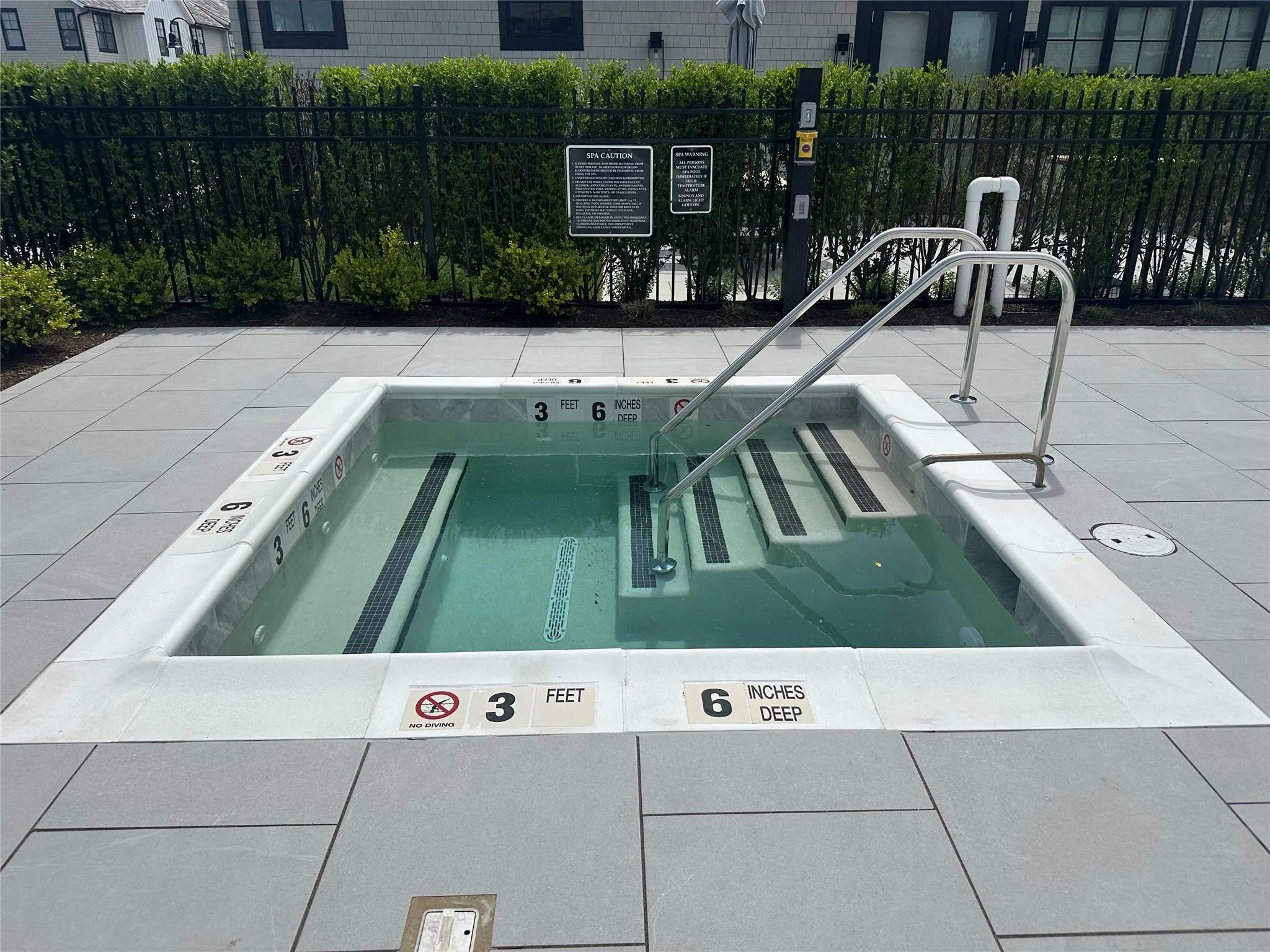 View of swimming pool with fence and a community hot tub View of swimming pool with fence and a community hot tub