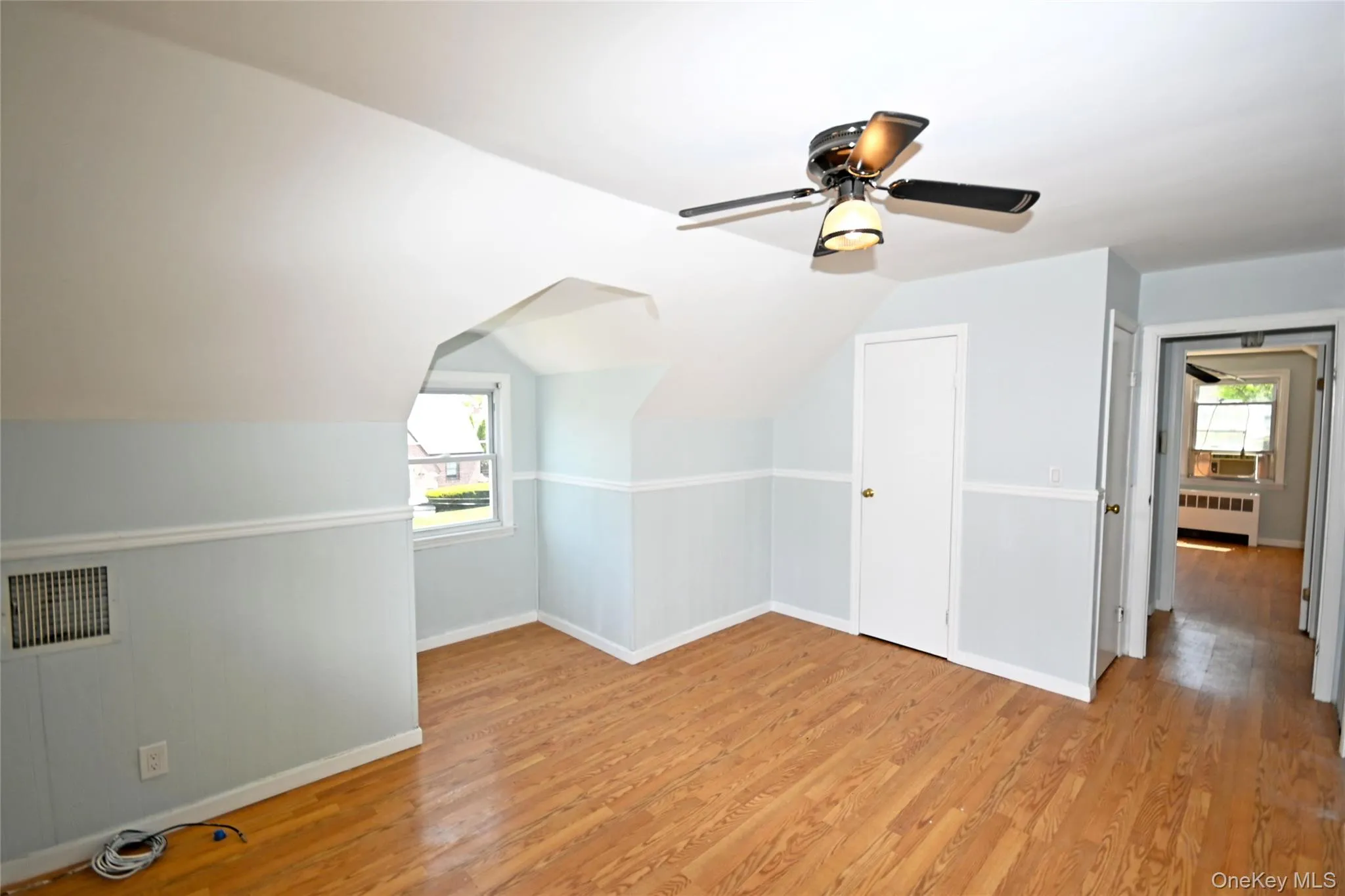 Additional living space with radiator, plenty of natural light, light wood-style floors, a ceiling fan, and lofted ceiling Additional living space with radiator, plenty of natural light, light wood-style floors, a ceiling fan, and lofted ceiling