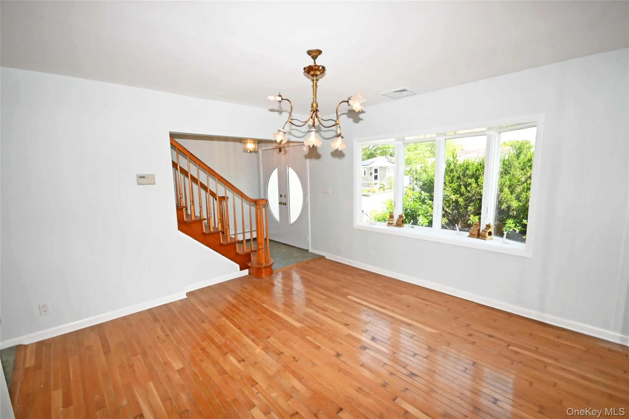 Foyer entrance with a chandelier, stairs, baseboards, and light wood-type flooring Foyer entrance with a chandelier, stairs, baseboards, and light wood-type flooring