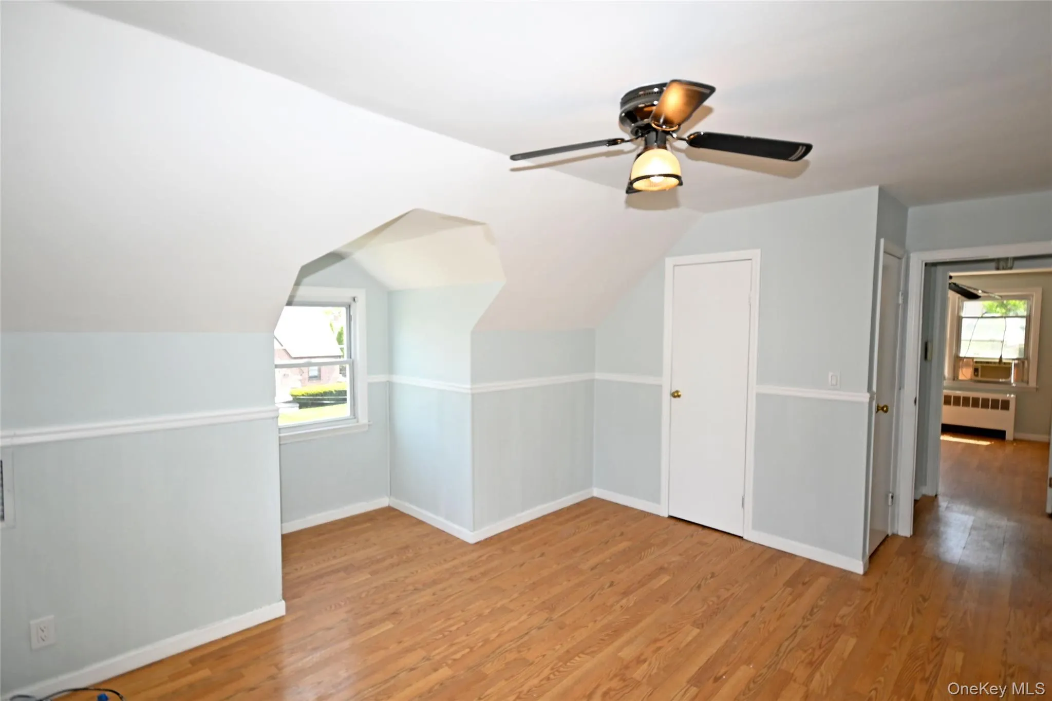 Additional living space featuring radiator, wood finished floors, baseboards, ceiling fan, and vaulted ceiling Additional living space featuring radiator, wood finished floors, baseboards, ceiling fan, and vaulted ceiling