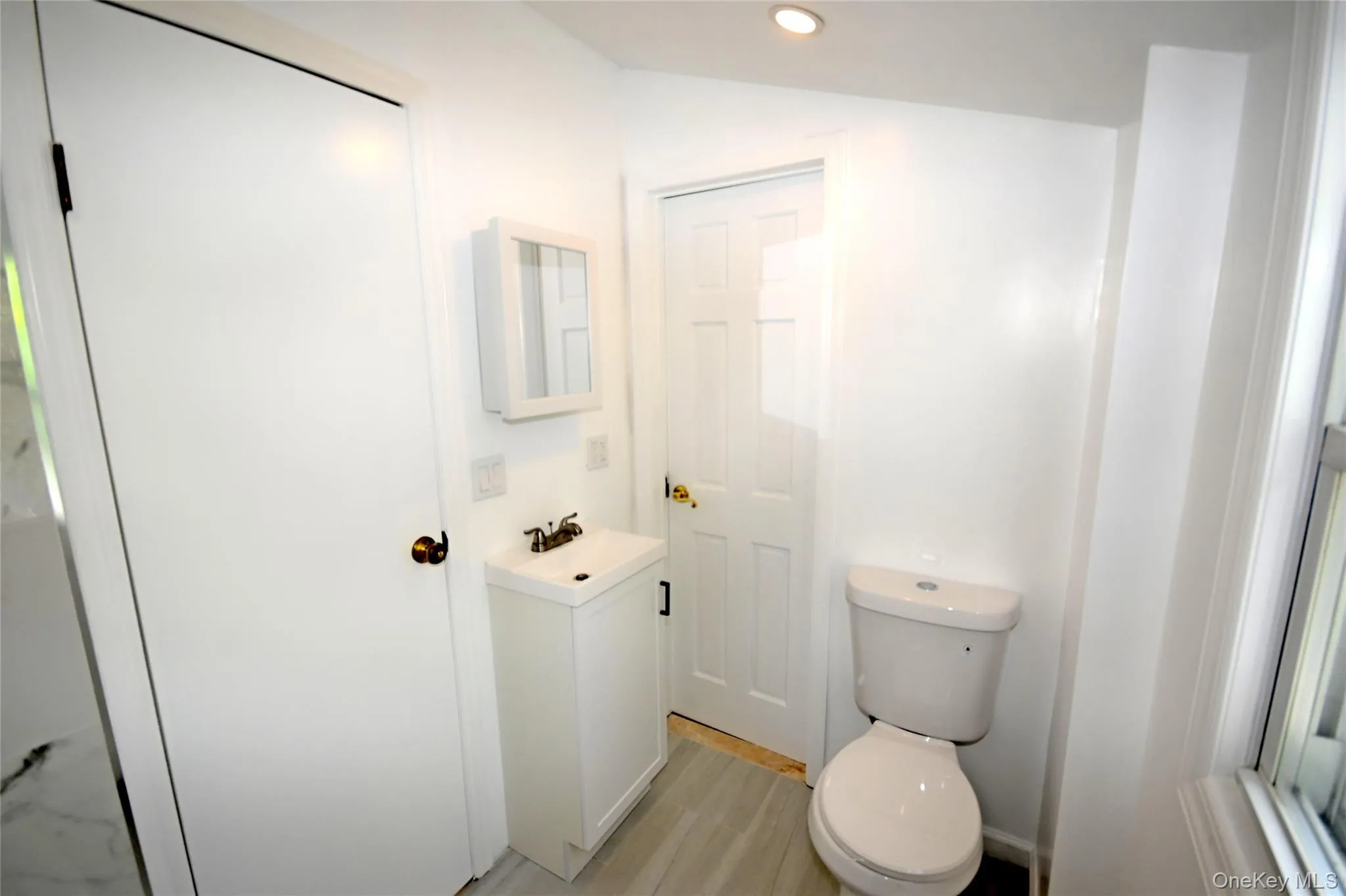 Bathroom featuring toilet, vanity, recessed lighting, and wood finished floors Bathroom featuring toilet, vanity, recessed lighting, and wood finished floors