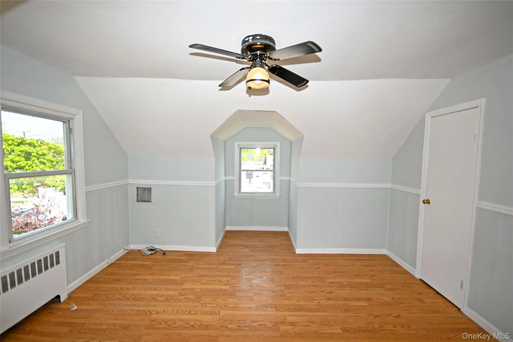 Additional living space with radiator, vaulted ceiling, light wood-style floors, a ceiling fan, and baseboards Additional living space with radiator, vaulted ceiling, light wood-style floors, a ceiling fan, and baseboards